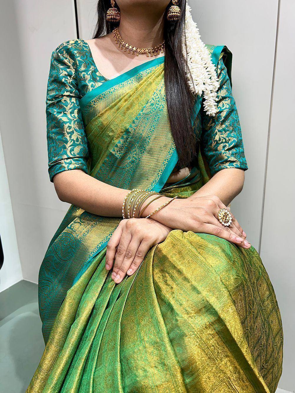 Green and gold designer saree with embroidered blouse, floral garland, and traditional jewelry