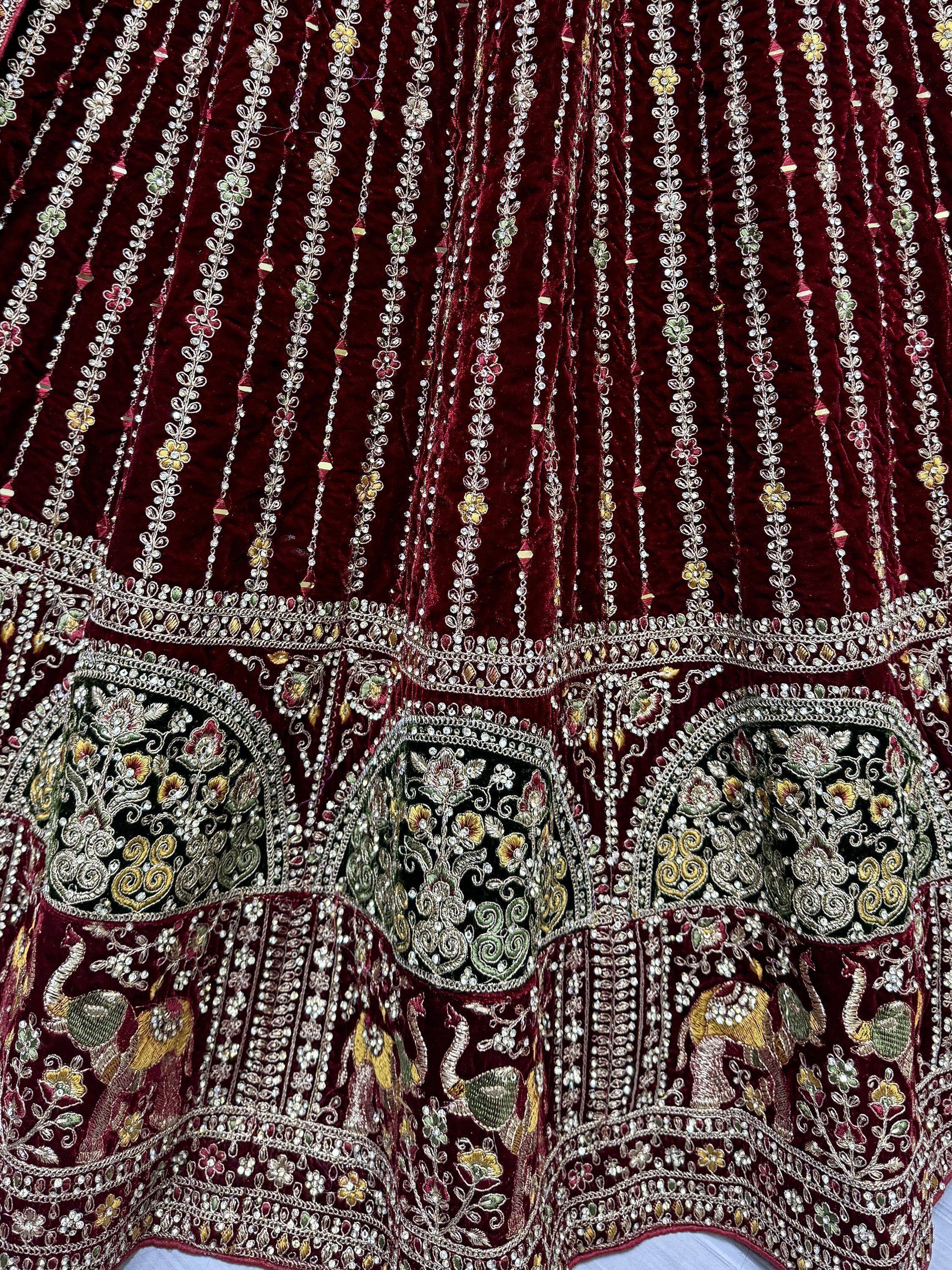 Rich maroon velvet lehenga with intricate floral embroidery, beadwork, and peacock motifs for Indian ethnic wear.