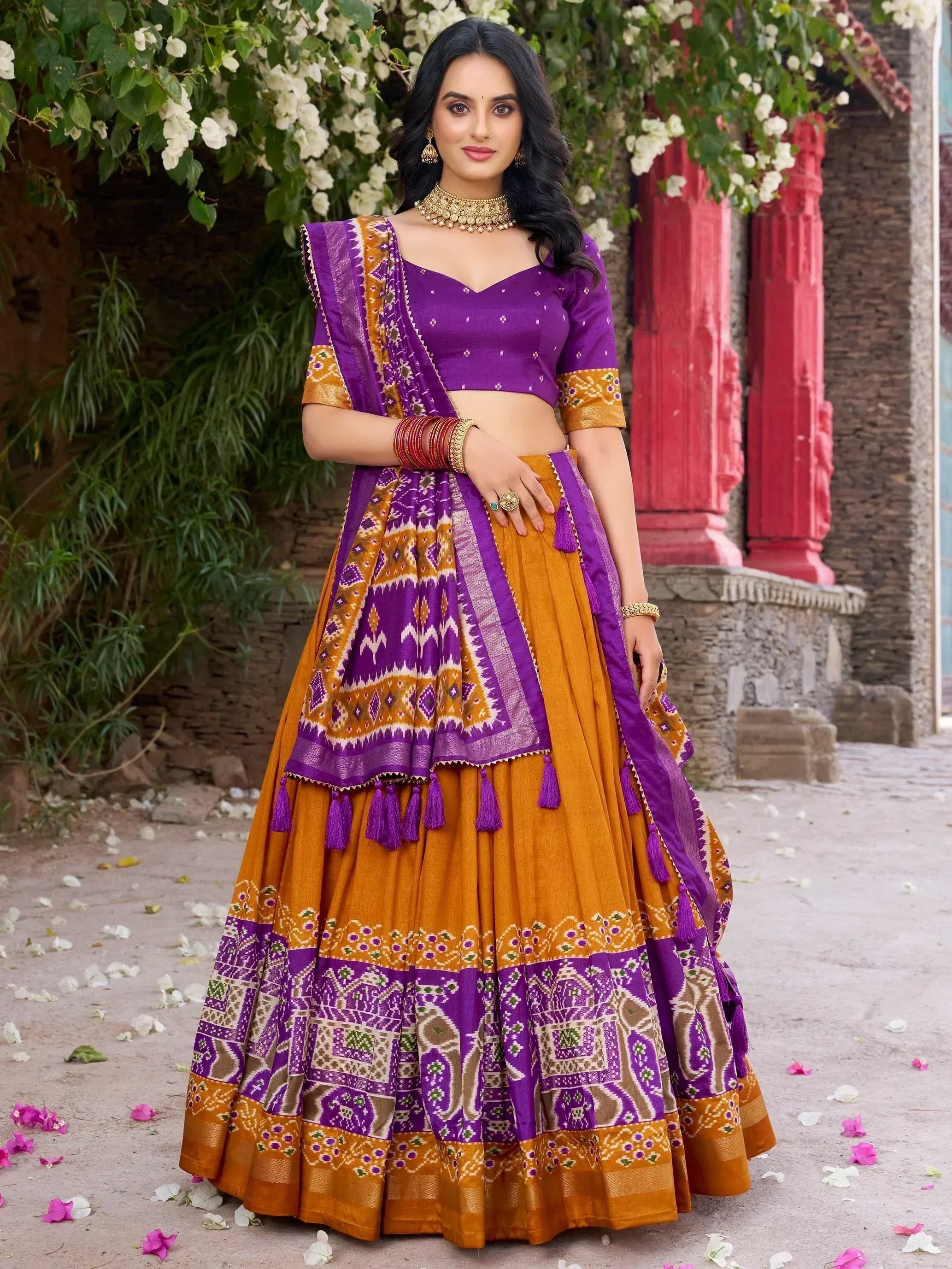 Purple and mustard Indian lehenga choli with ikat print, tassels, and ethnic jewelry for festive occasions