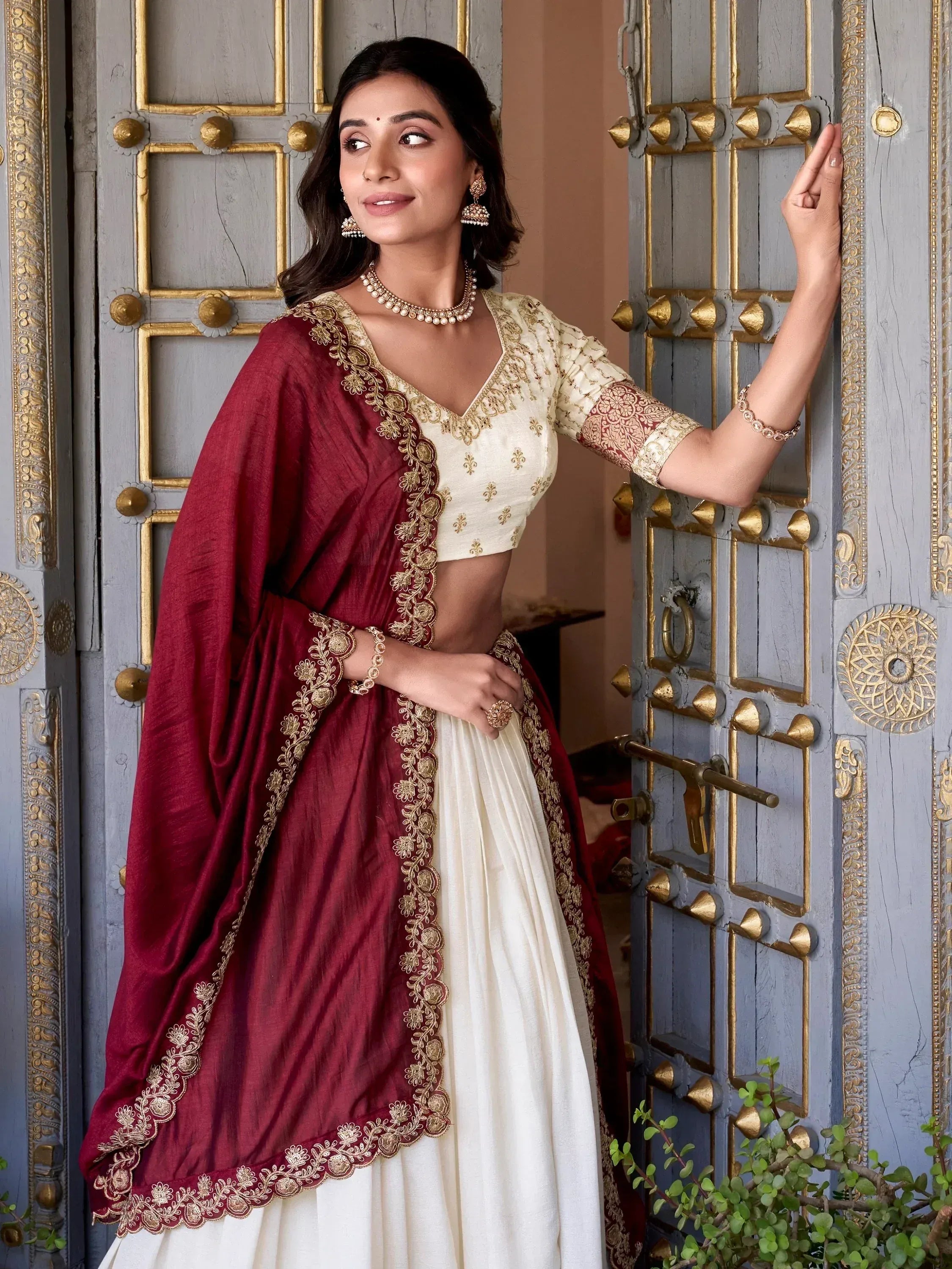 Elegant ivory and maroon lehenga choli with gold embroidery, perfect for Indian ethnic wear occasions.