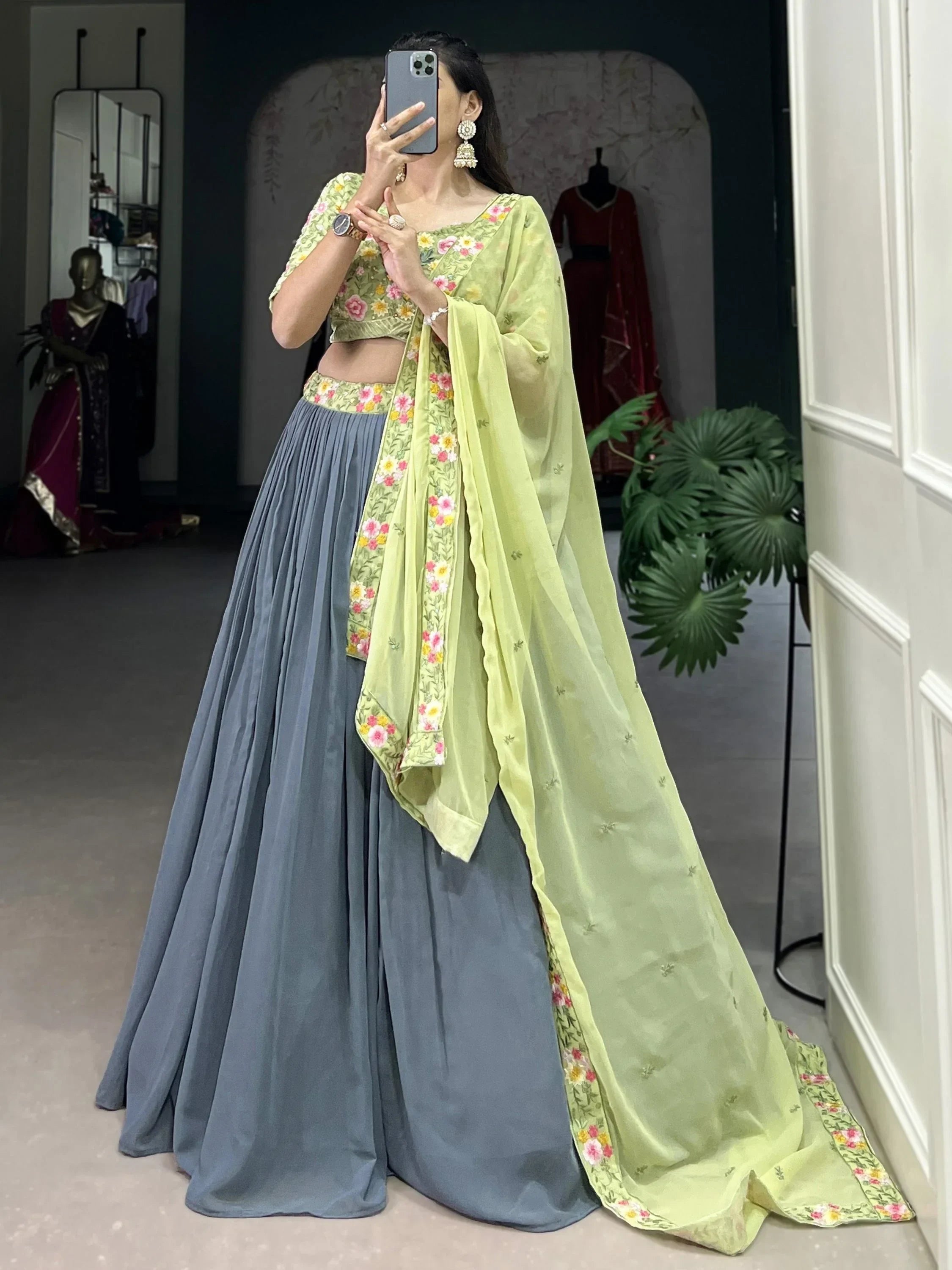 Woman in floral green crop top with blue pleated skirt and matching dupatta, Indian ethnic wear