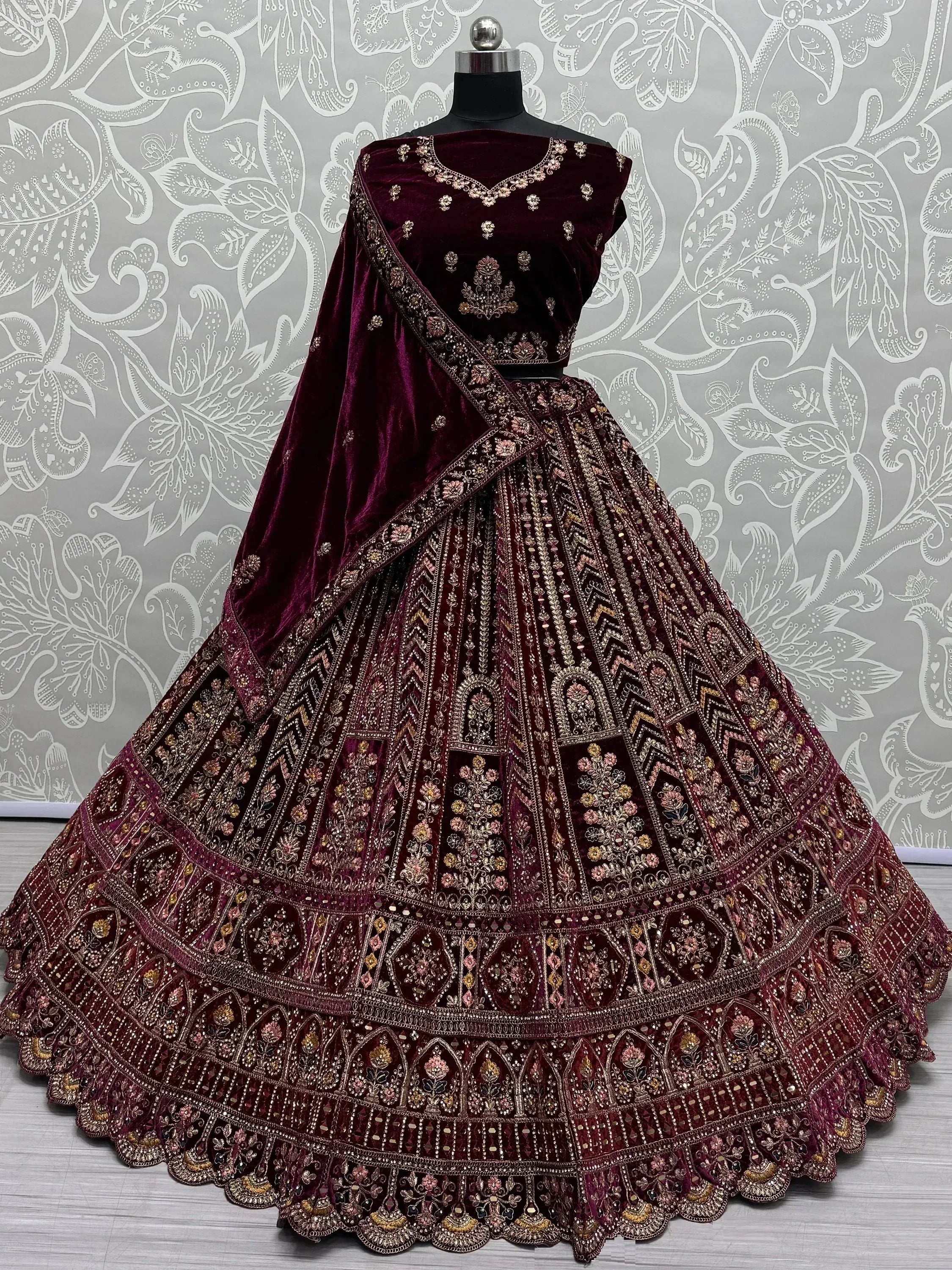Burgundy velvet lehenga choli with heavy gold embroidery, perfect for Indian weddings and festive occasions.