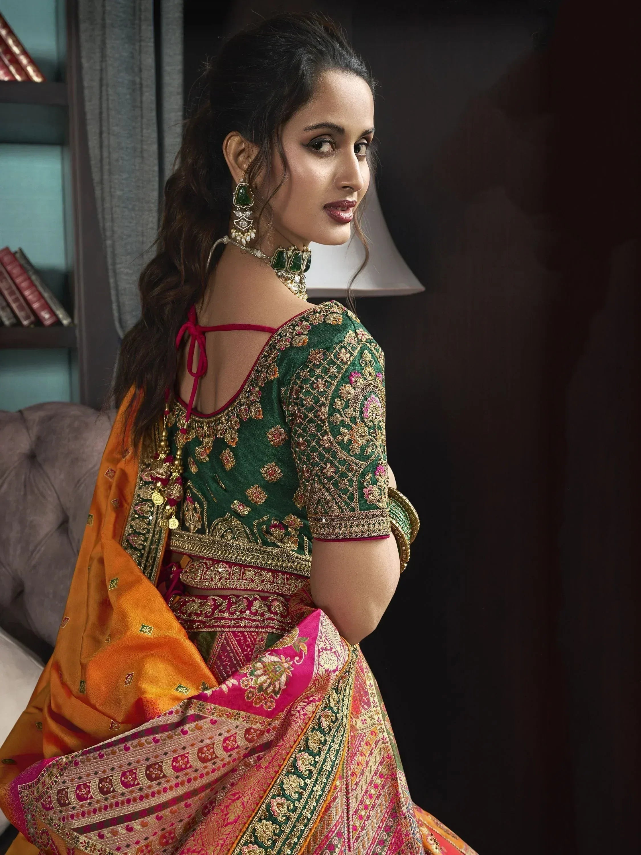 Woman in green embroidered lehenga choli with orange dupatta, traditional Indian ethnic wear