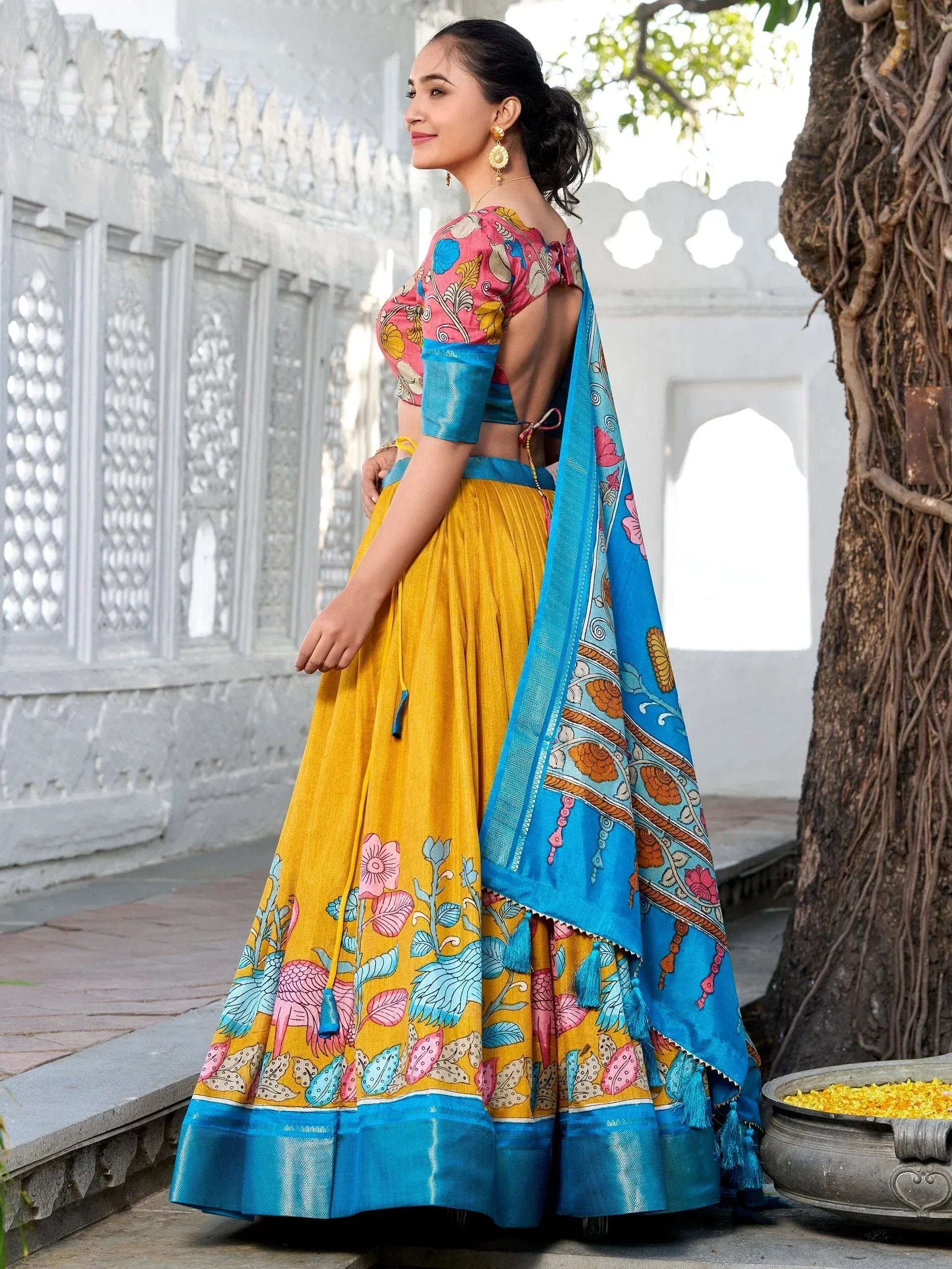 Woman in vibrant yellow and blue printed lehenga choli with floral motifs, perfect for ethnic occasions