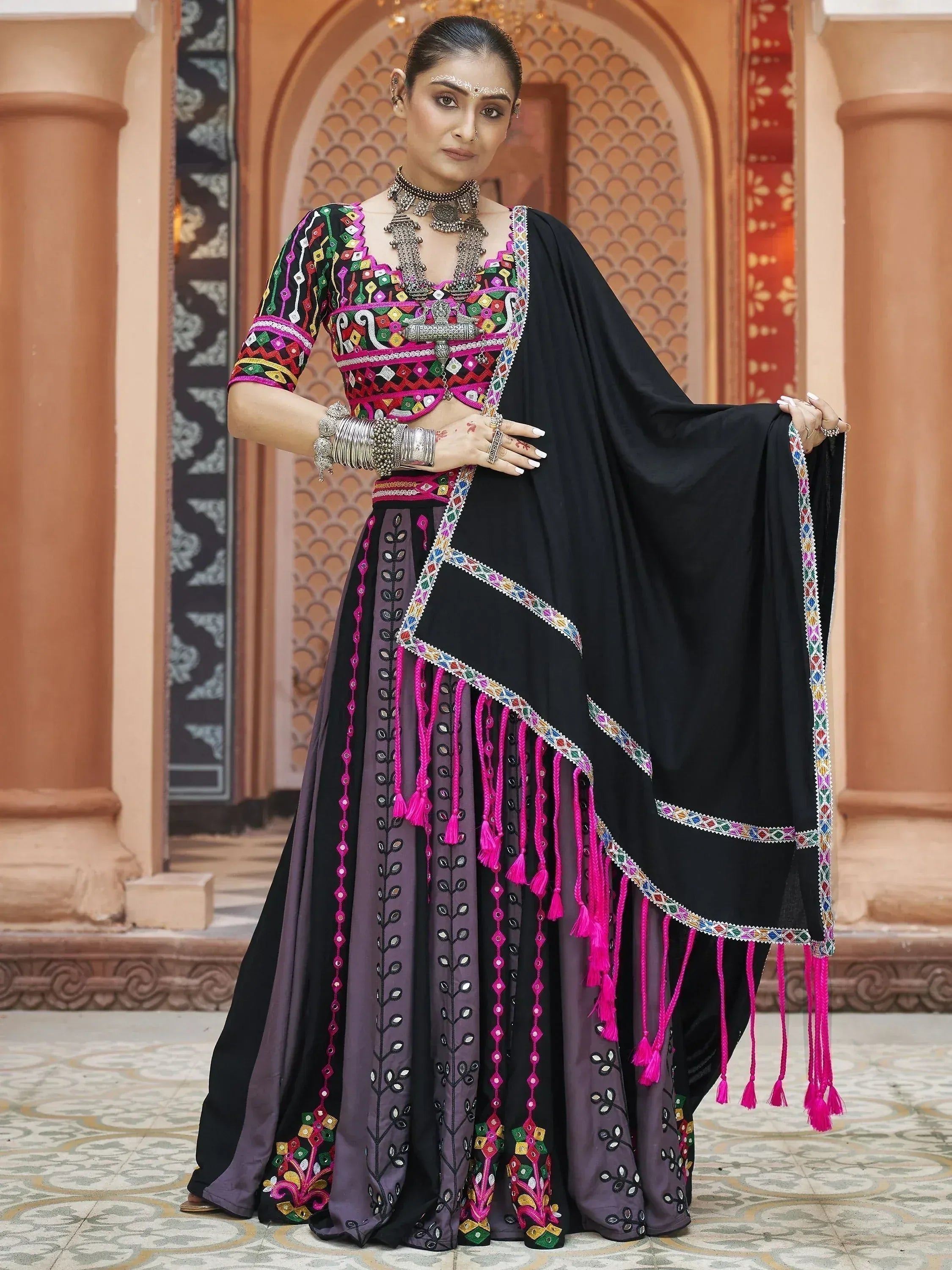 Black and purple embroidered lehenga choli with mirror work and pink tassels, traditional Indian ethnic wear