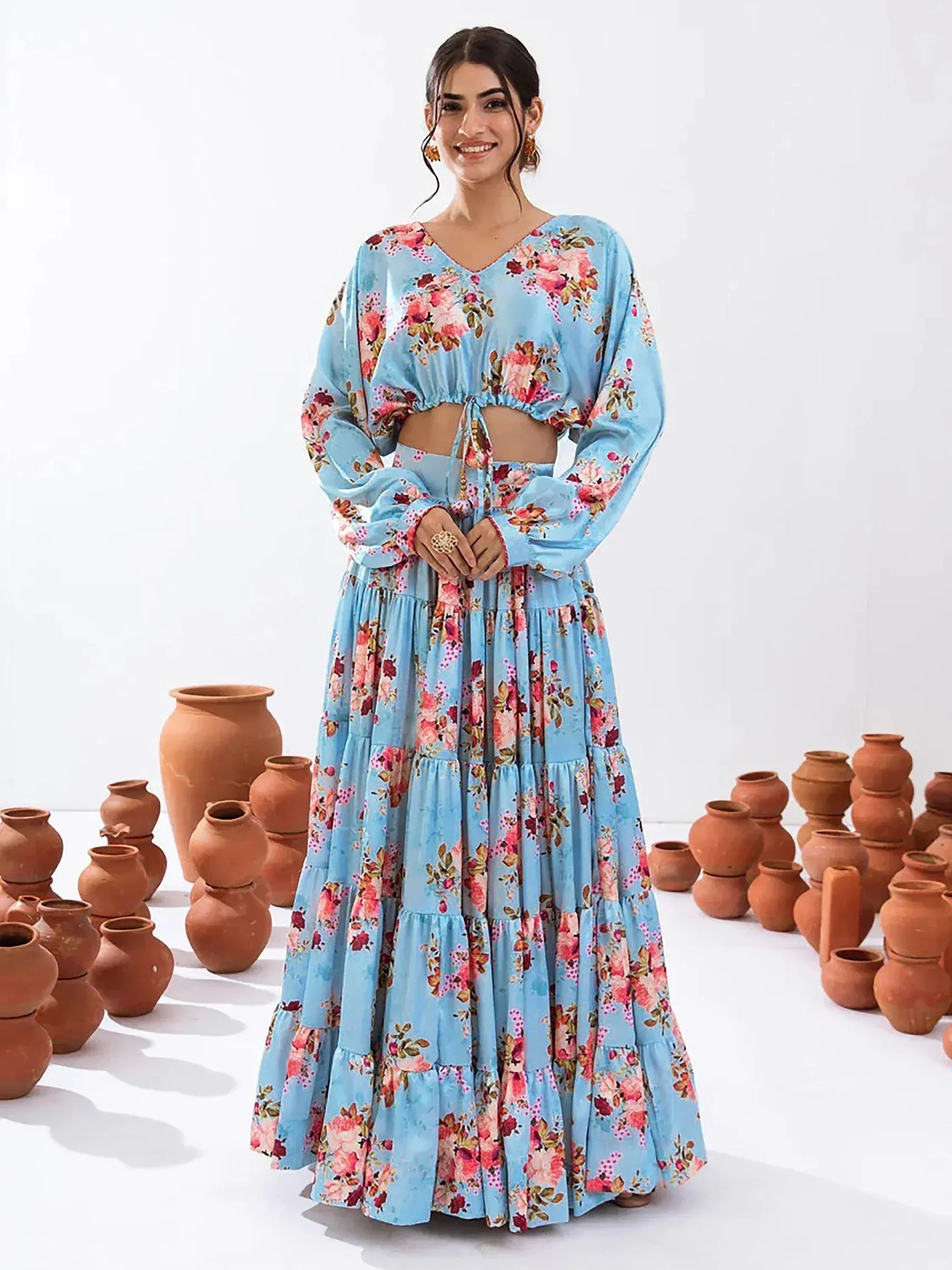 Blue floral ethnic gown with ruffled layers and long sleeves, styled with terracotta pots