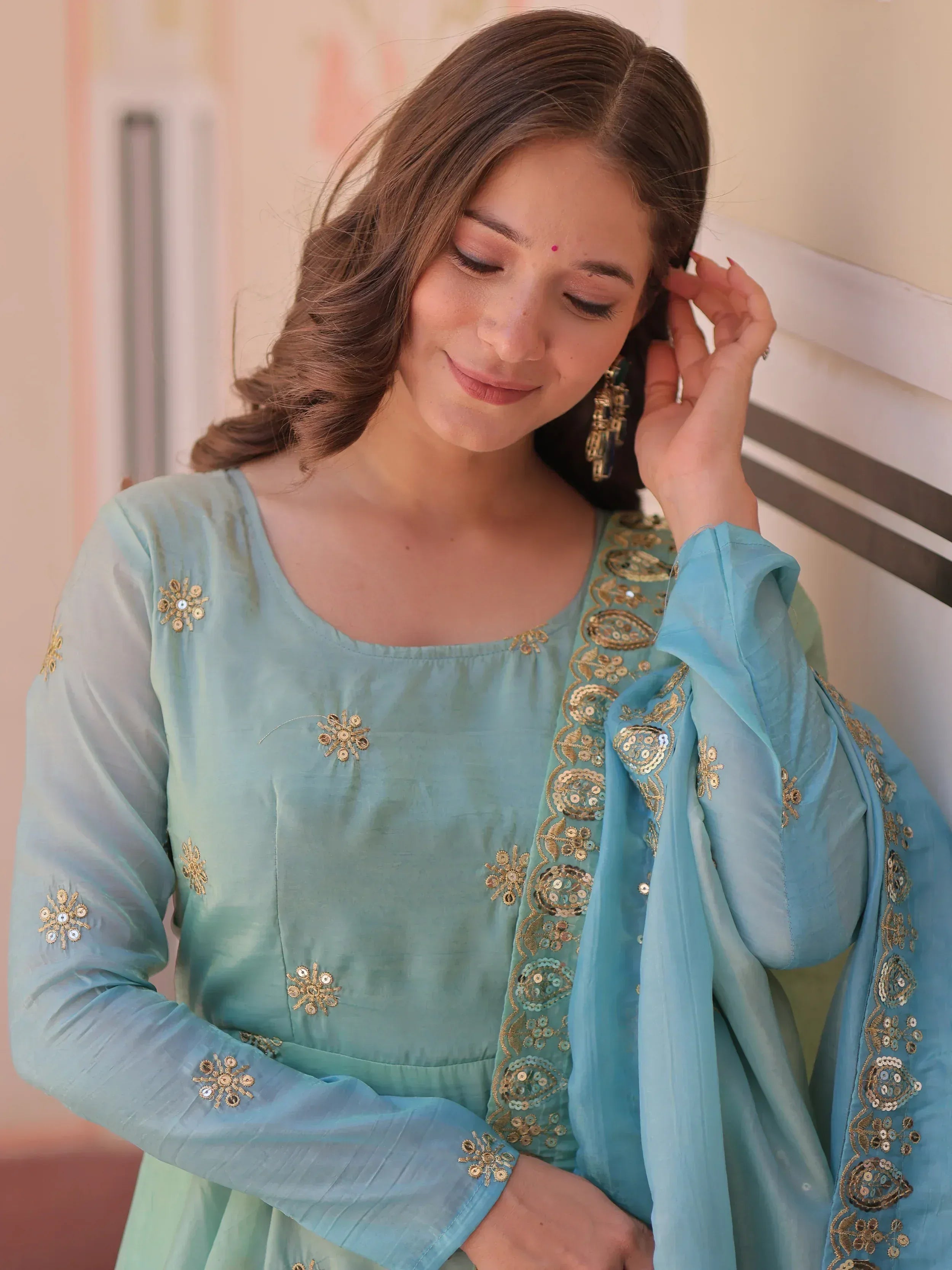 Woman in light blue embroidered salwar kameez with gold detailing, perfect for Indian ethnic wear occasions.