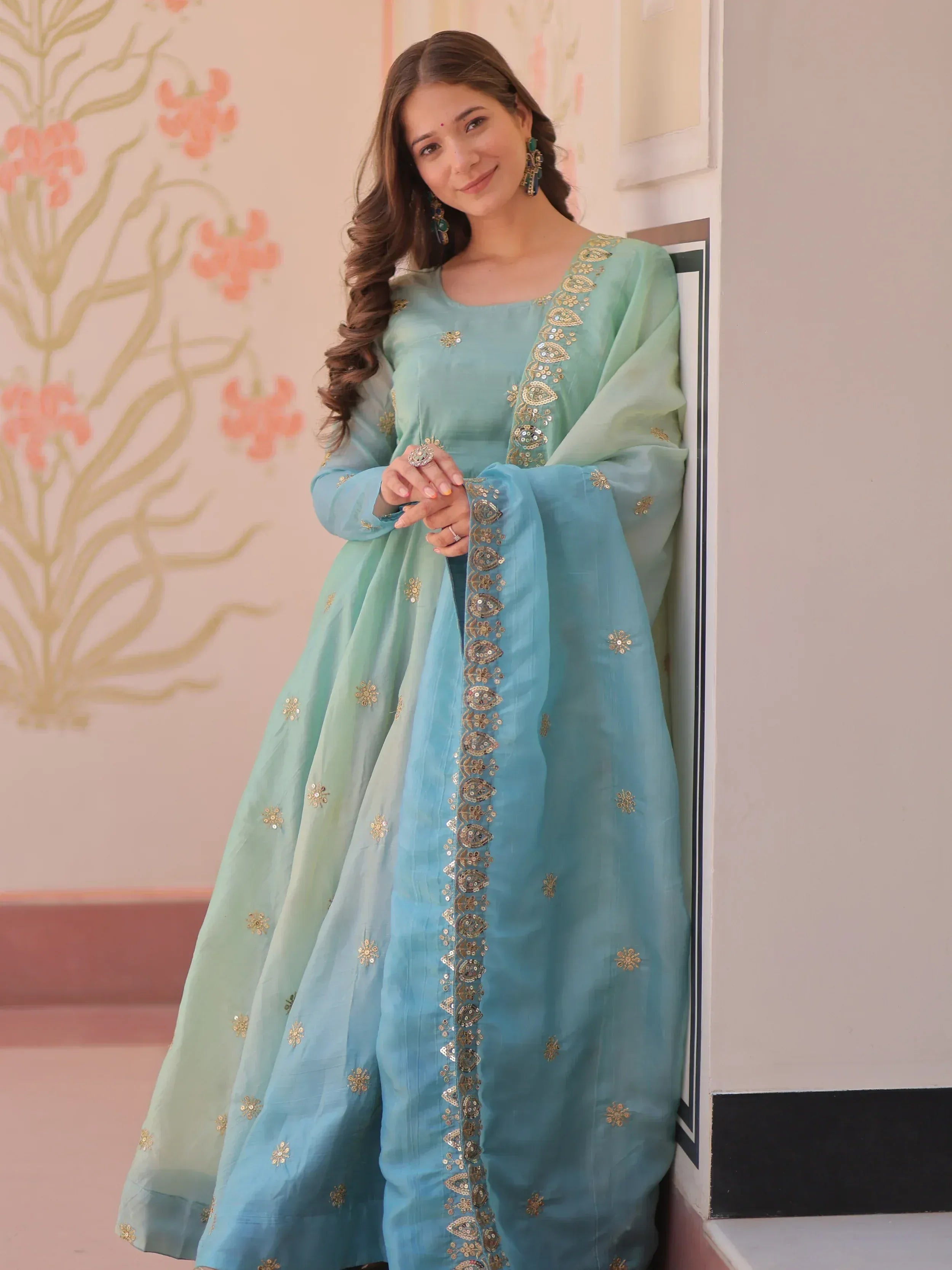 Woman in mint blue embroidered Anarkali suit with gold detailing, perfect for Indian ethnic occasions.