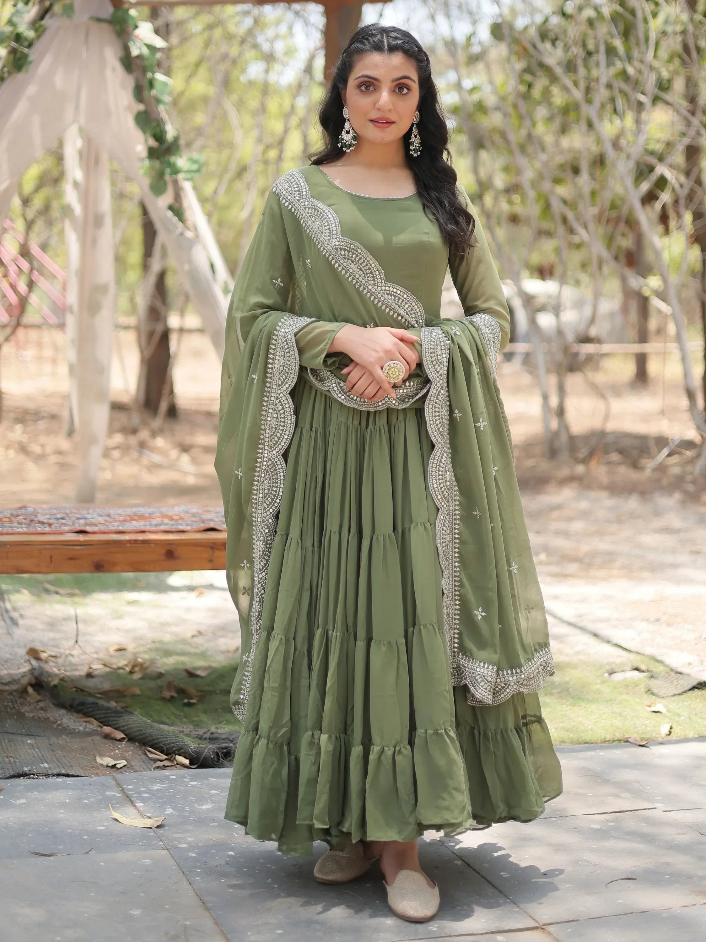 Woman in olive green embroidered ethnic gown with dupatta, standing outdoors
