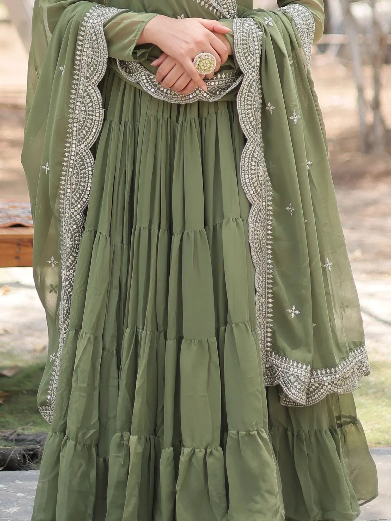 Olive green embroidered lehenga with dupatta and statement ring, outdoor setting
