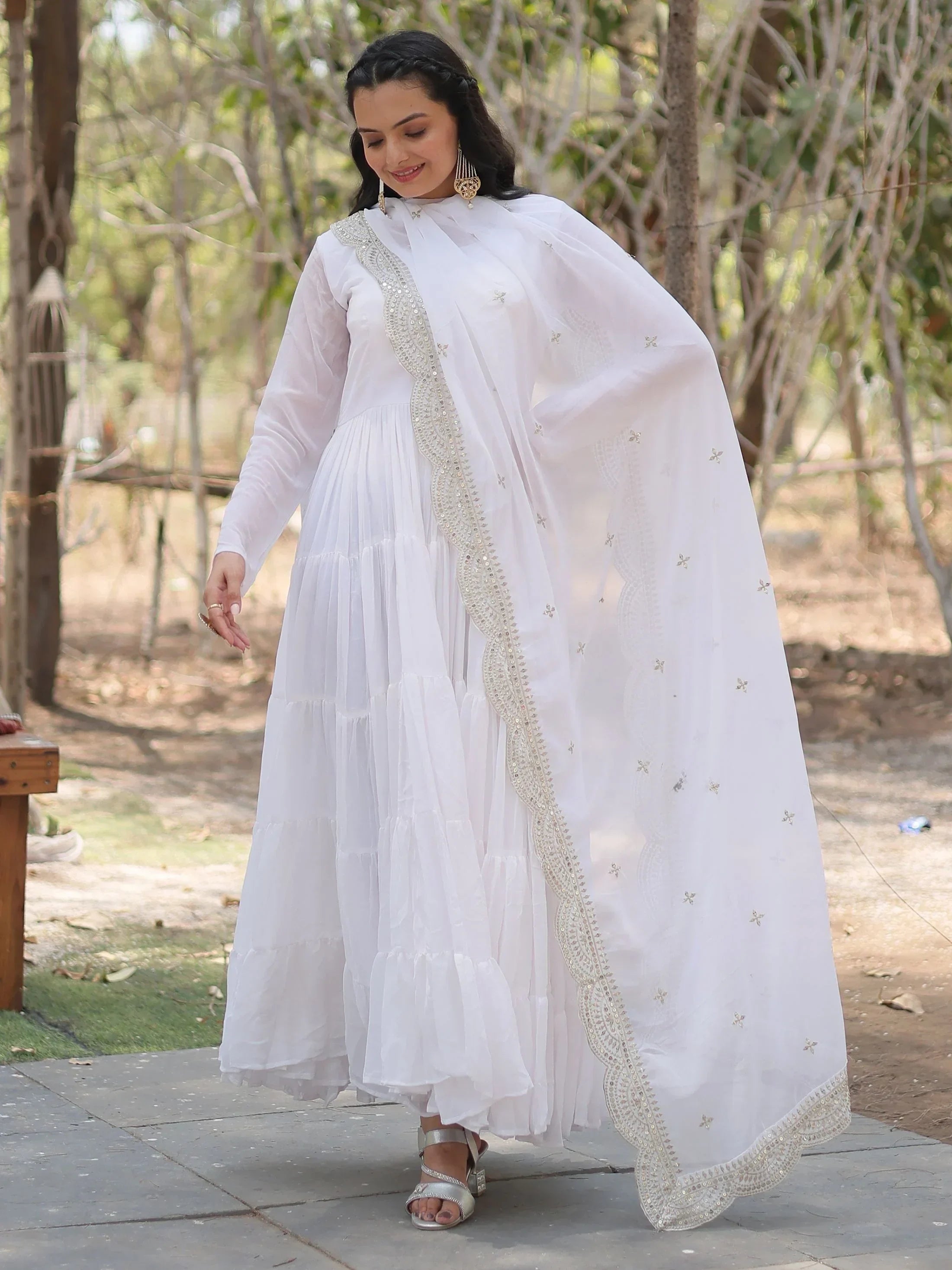 Woman in white Anarkali suit with dupatta and silver embroidery, outdoor setting