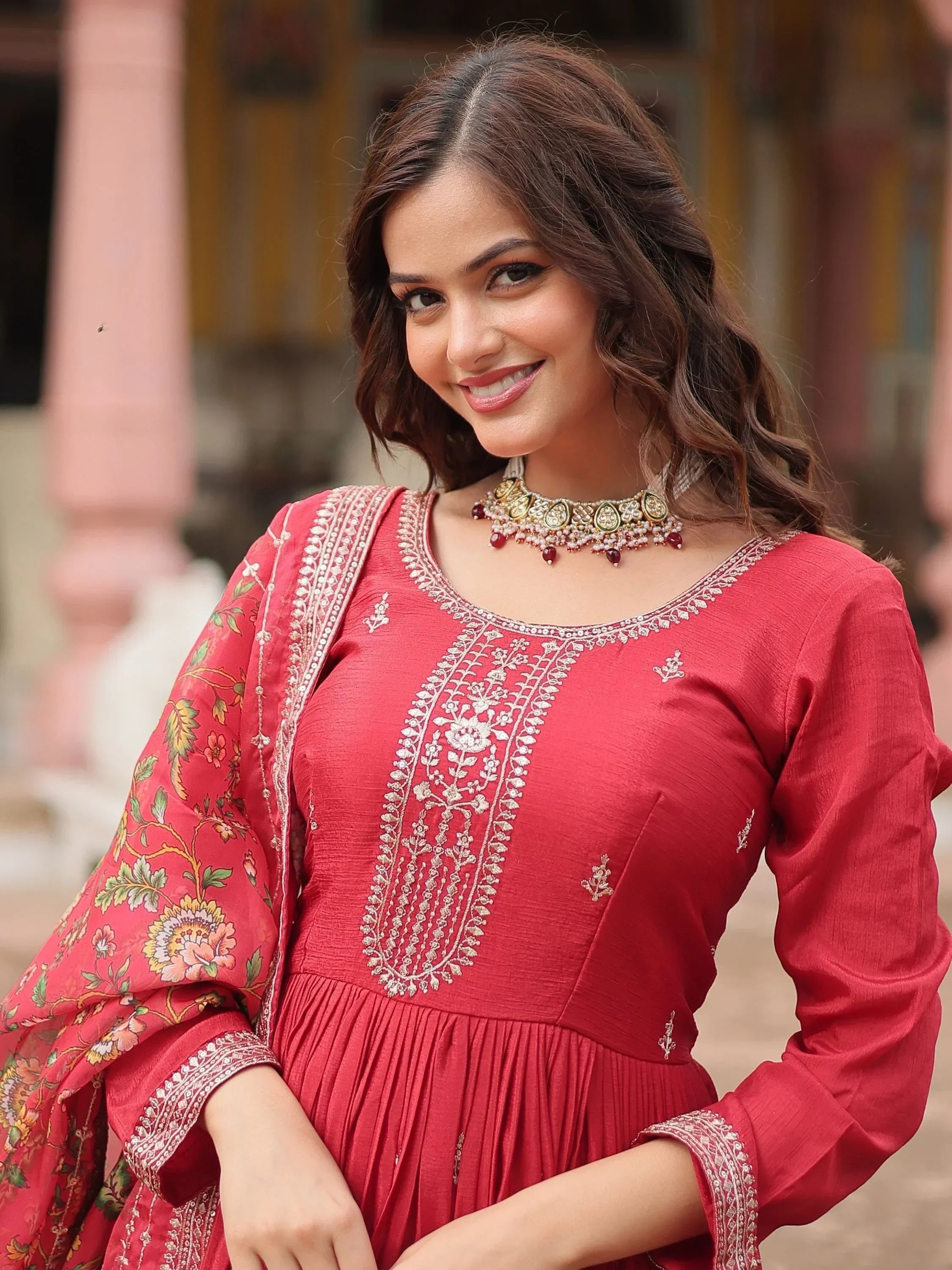 Woman in maroon embroidered ethnic gown with floral dupatta, traditional jewelry