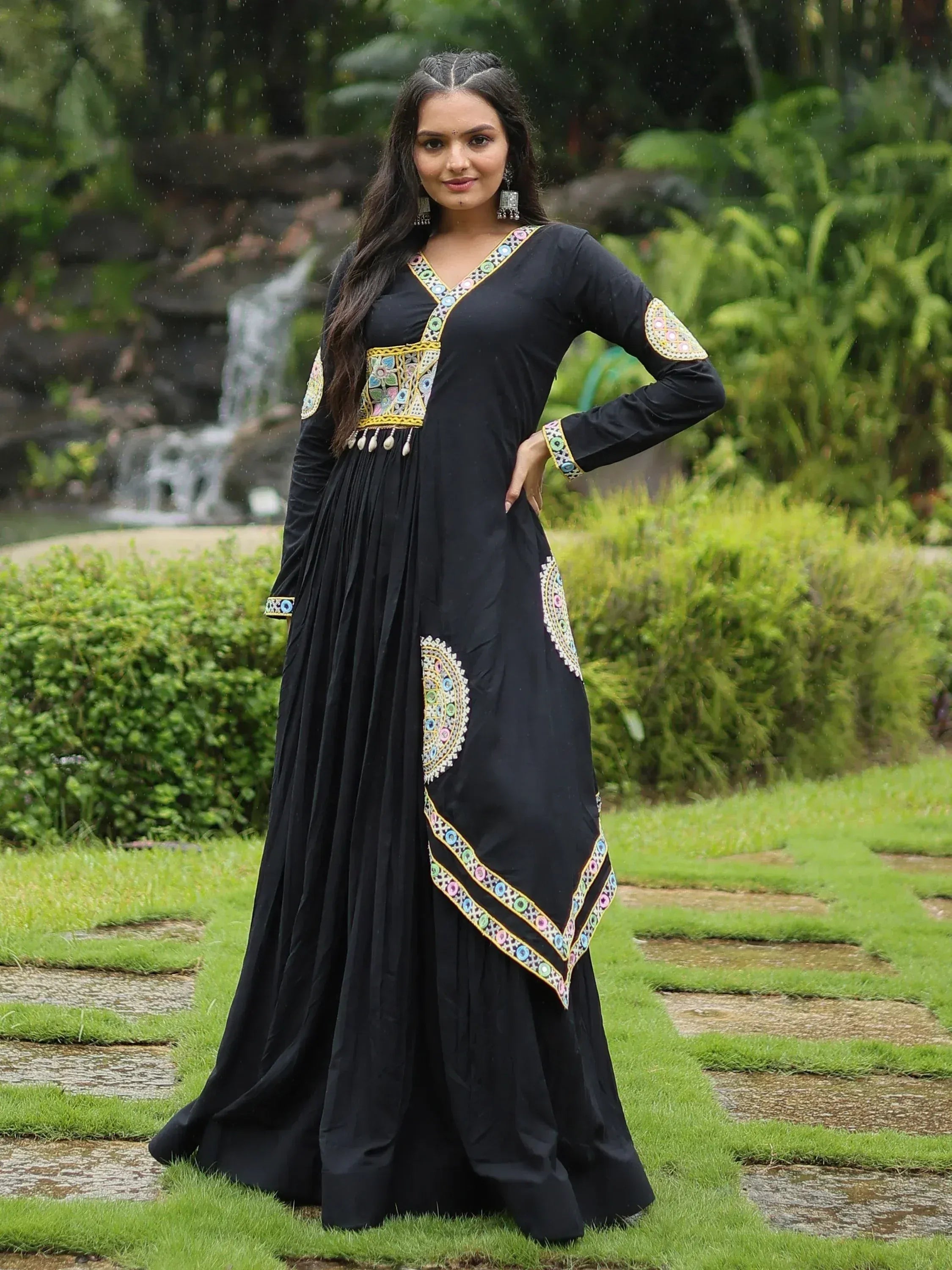 Black ethnic gown with colorful mirror work, perfect for Indian occasions, styled in a garden setting.