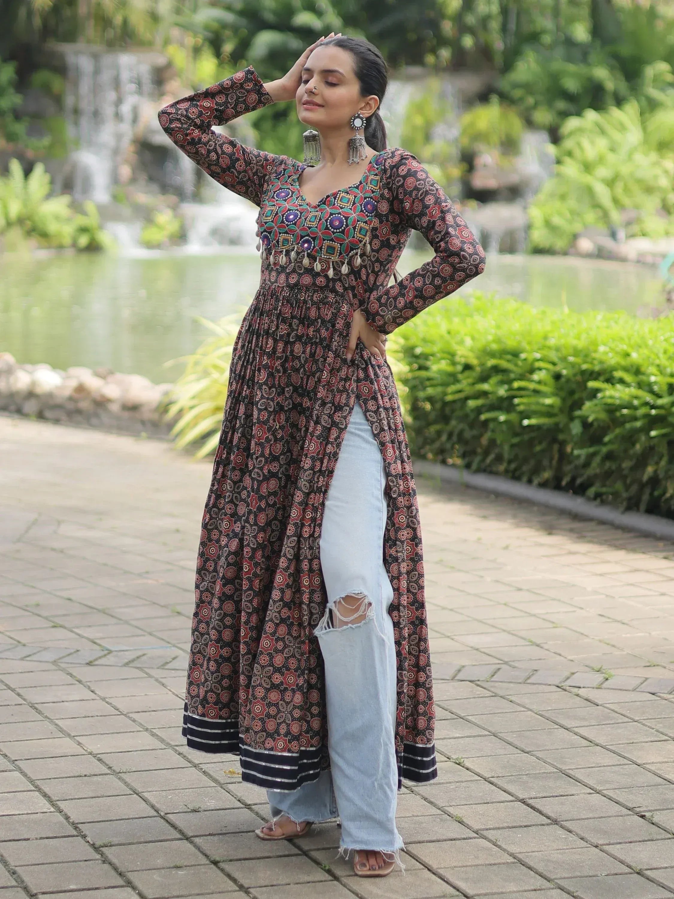 Woman in printed ethnic kurta with mirror work, paired with ripped jeans, standing in garden