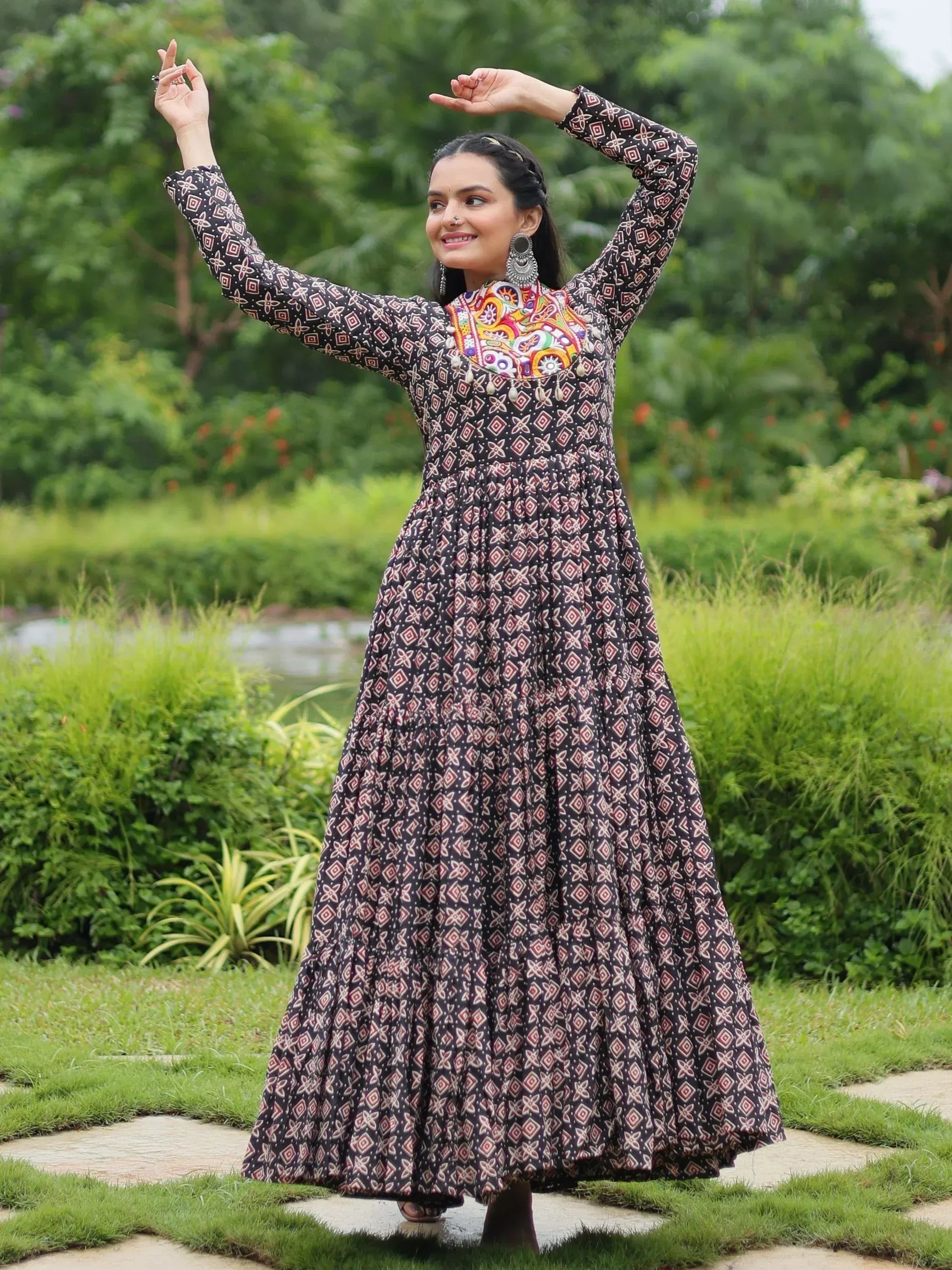 Woman in ethnic printed gown with colorful neckline, dancing in garden