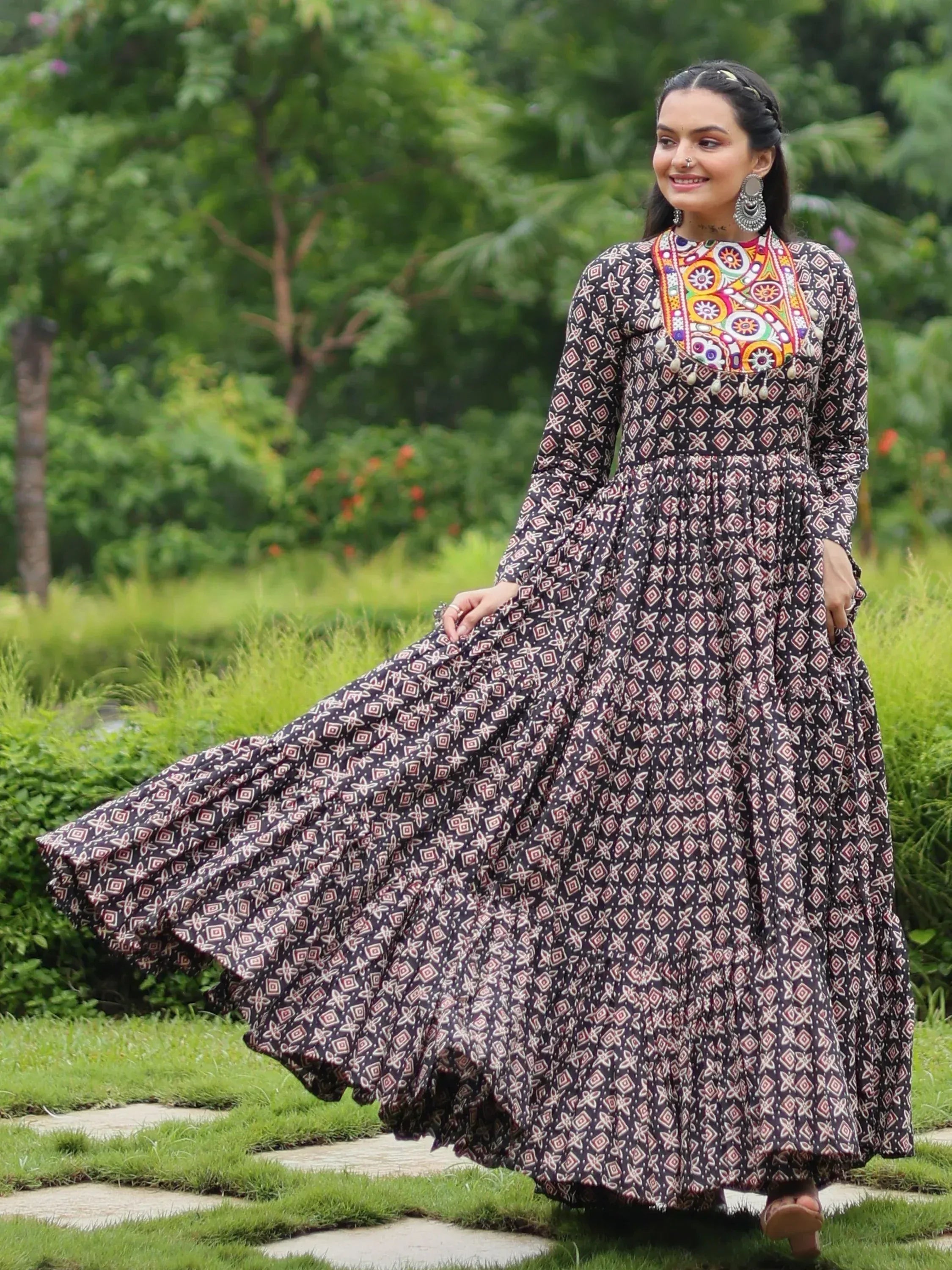 Woman in ethnic printed gown with colorful embroidery, walking in garden