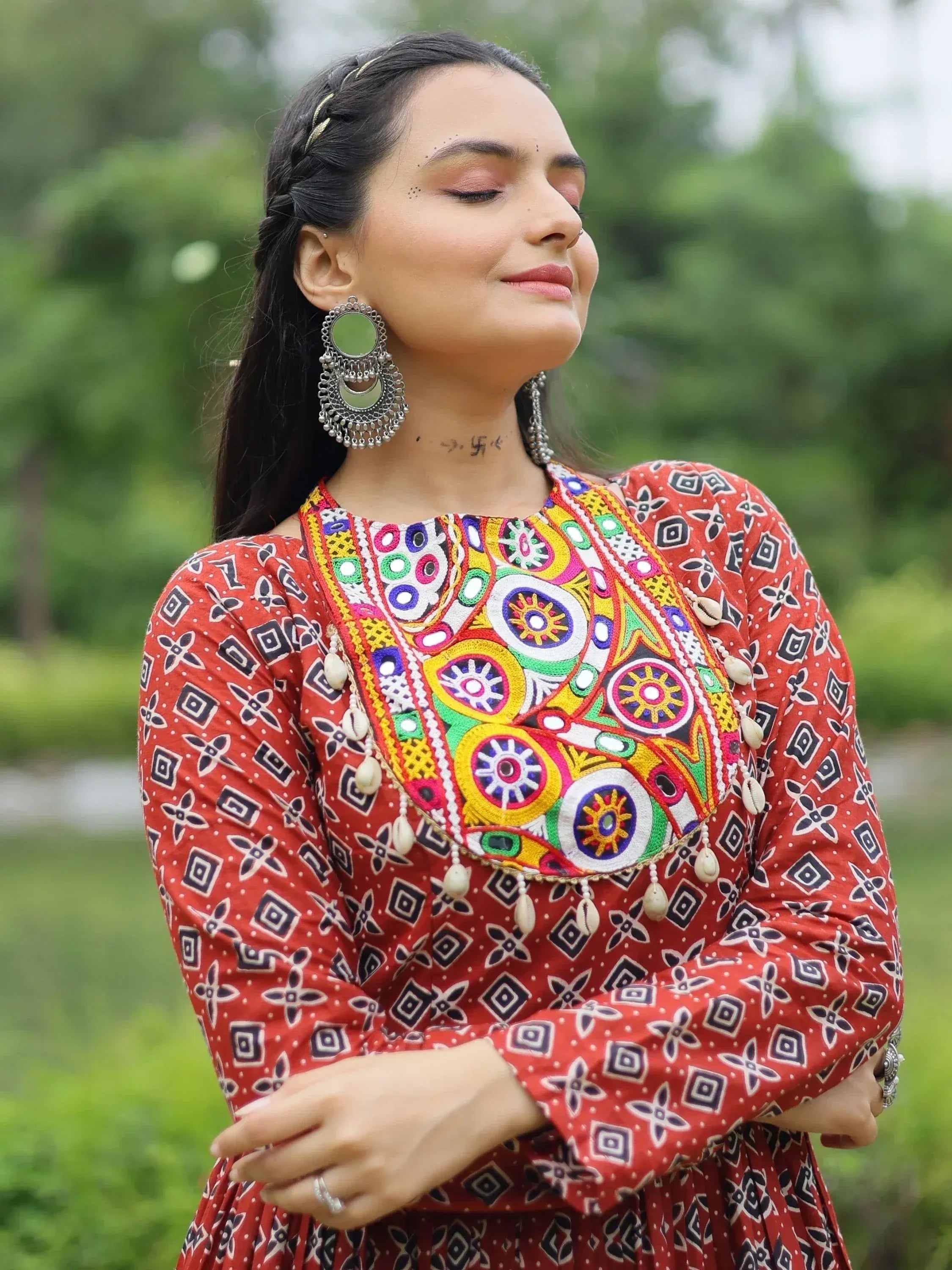 Woman in vibrant red ethnic kurta with colorful mirror embroidery and shell detailing, styled with jhumka earrings