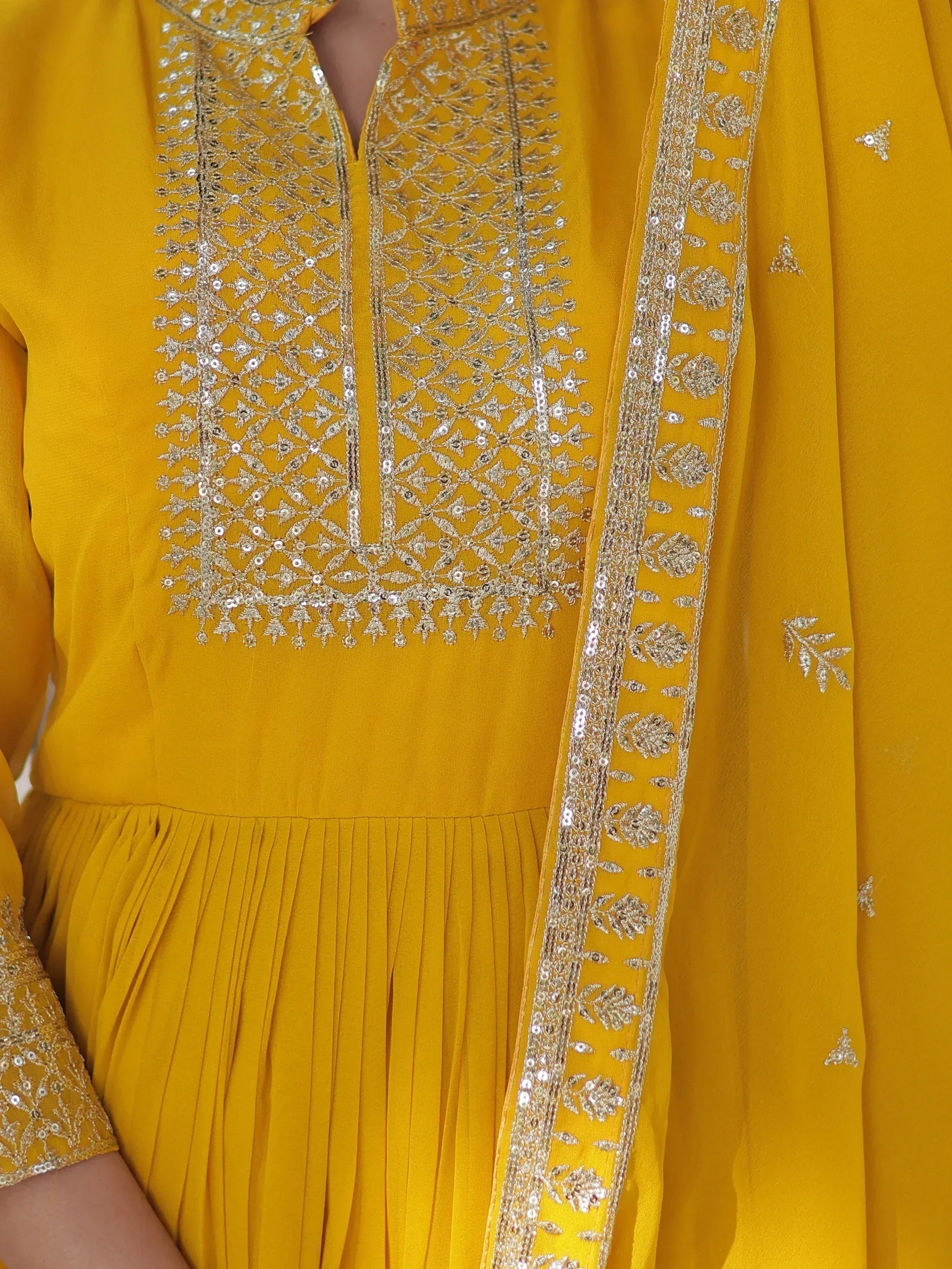 Yellow ethnic gown with intricate gold embroidery and sequin detailing, perfect for Indian festive occasions.