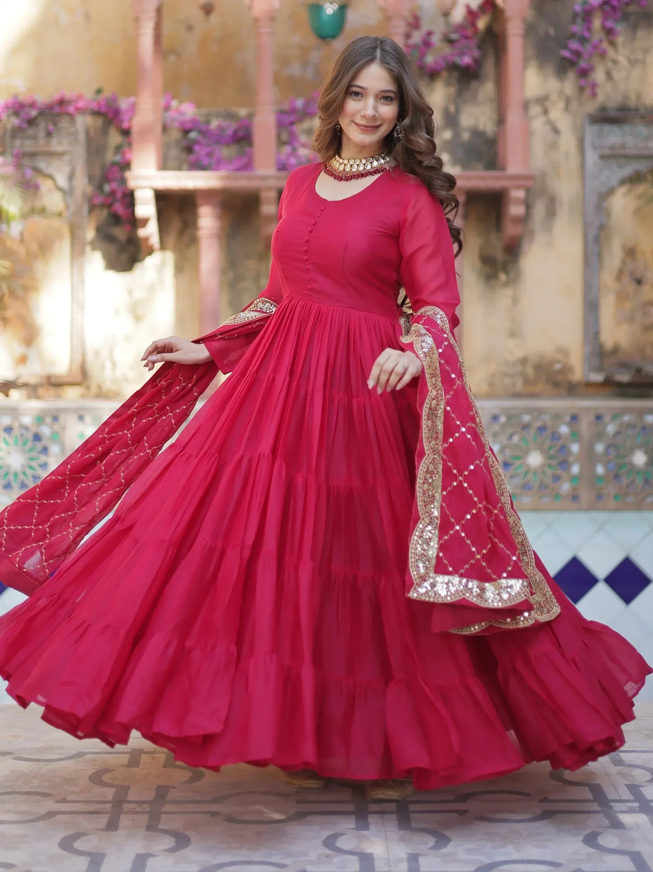 Red ethnic gown with gold embroidery, pleated skirt, and flared sleeves for Indian occasions