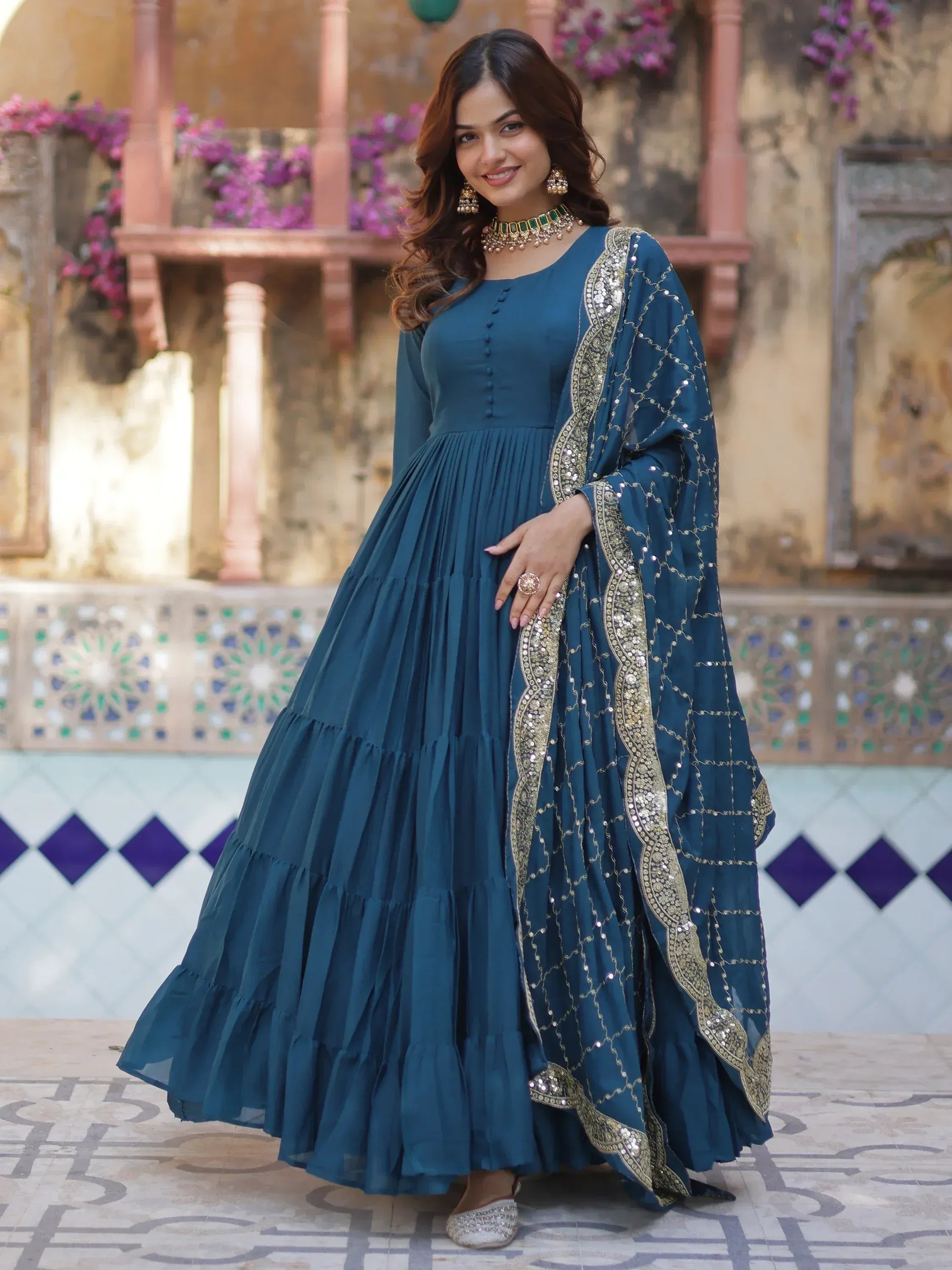 Teal blue ethnic gown with gold embroidery, pleated skirt, and matching dupatta for Indian occasions