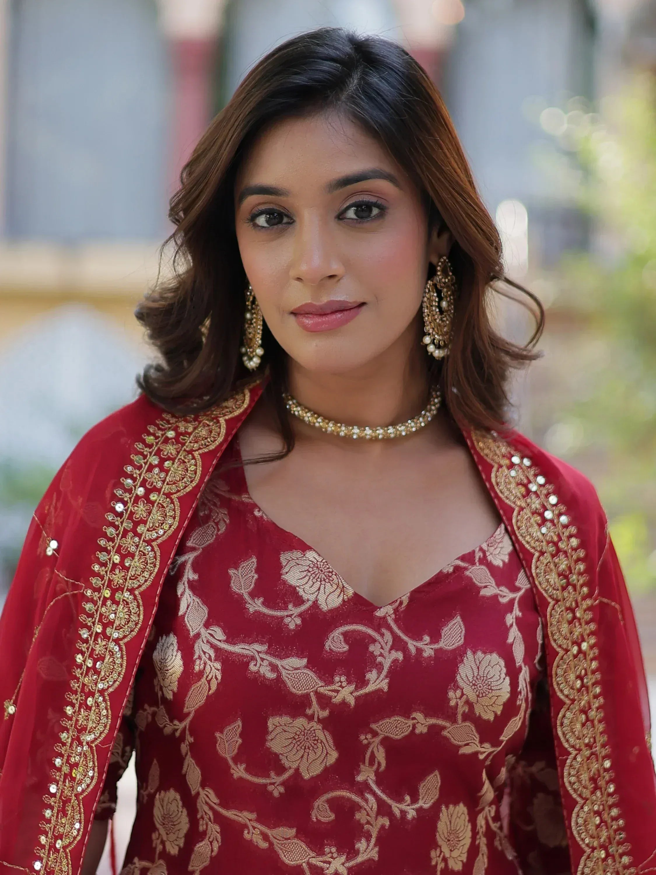 Red floral embroidered ethnic gown with gold detailing and matching jewelry
