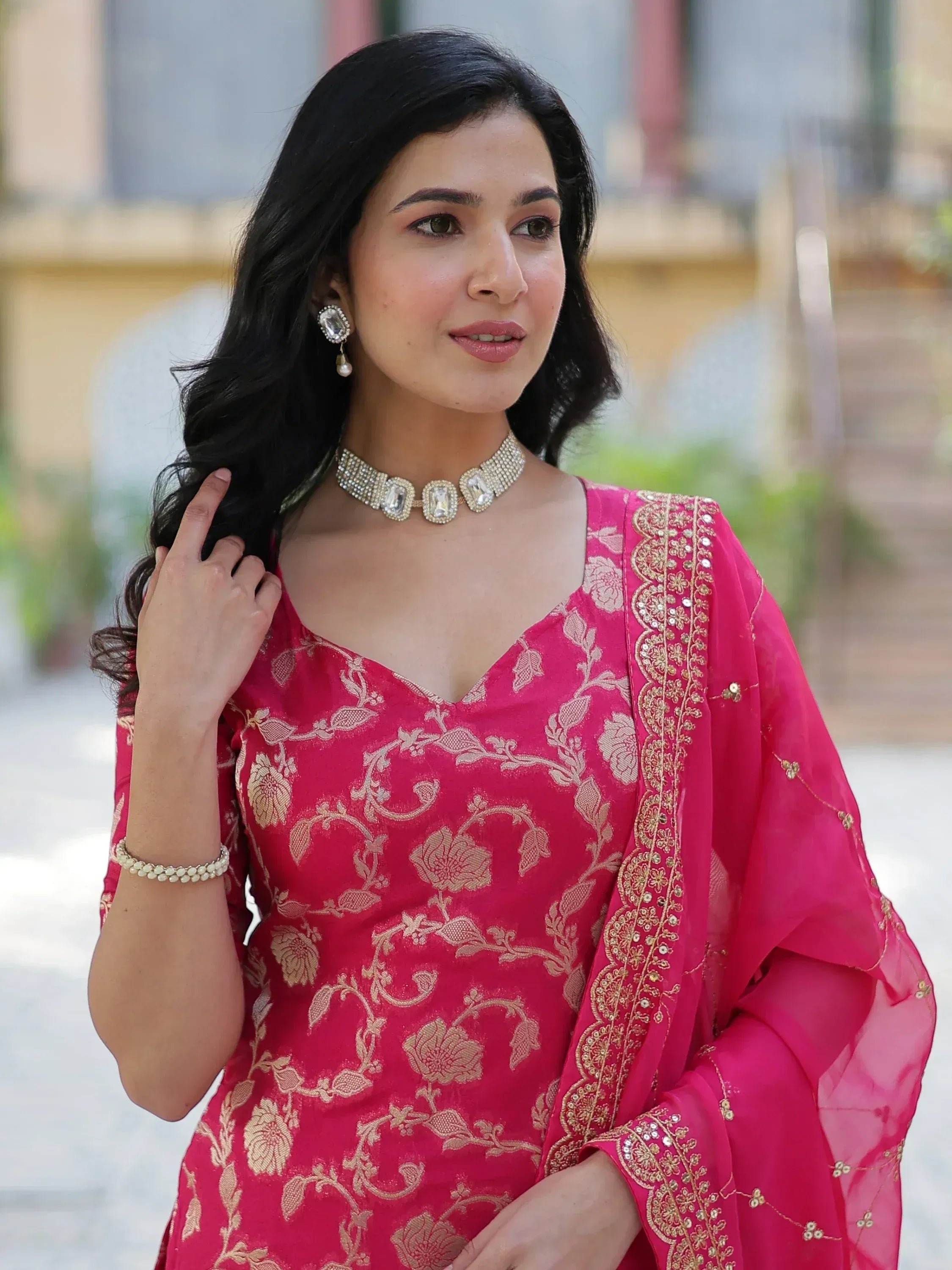 Woman in pink floral ethnic gown with gold embroidery and statement jewelry