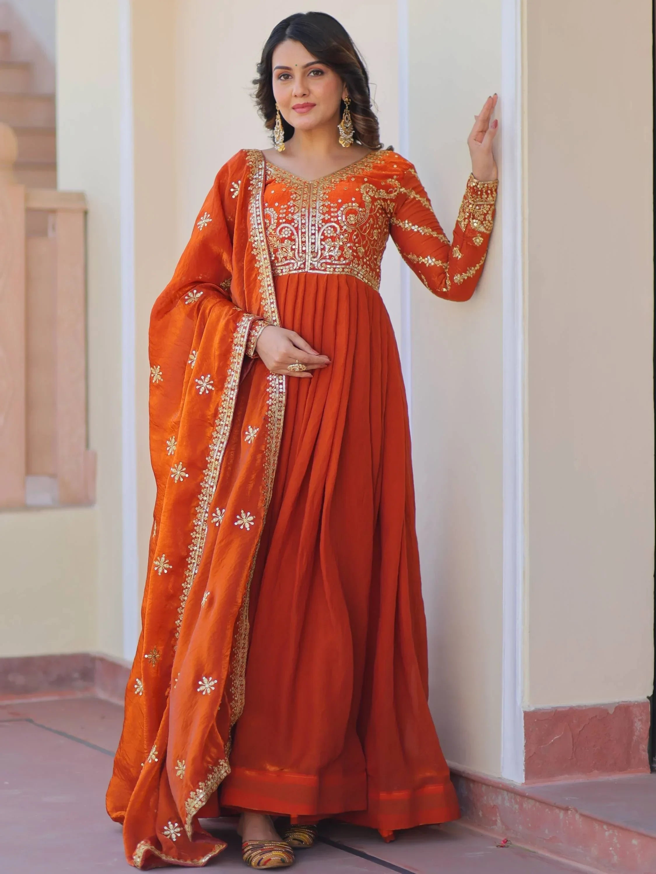 Woman wearing orange embroidered Anarkali suit with matching dupatta and ethnic jewelry
