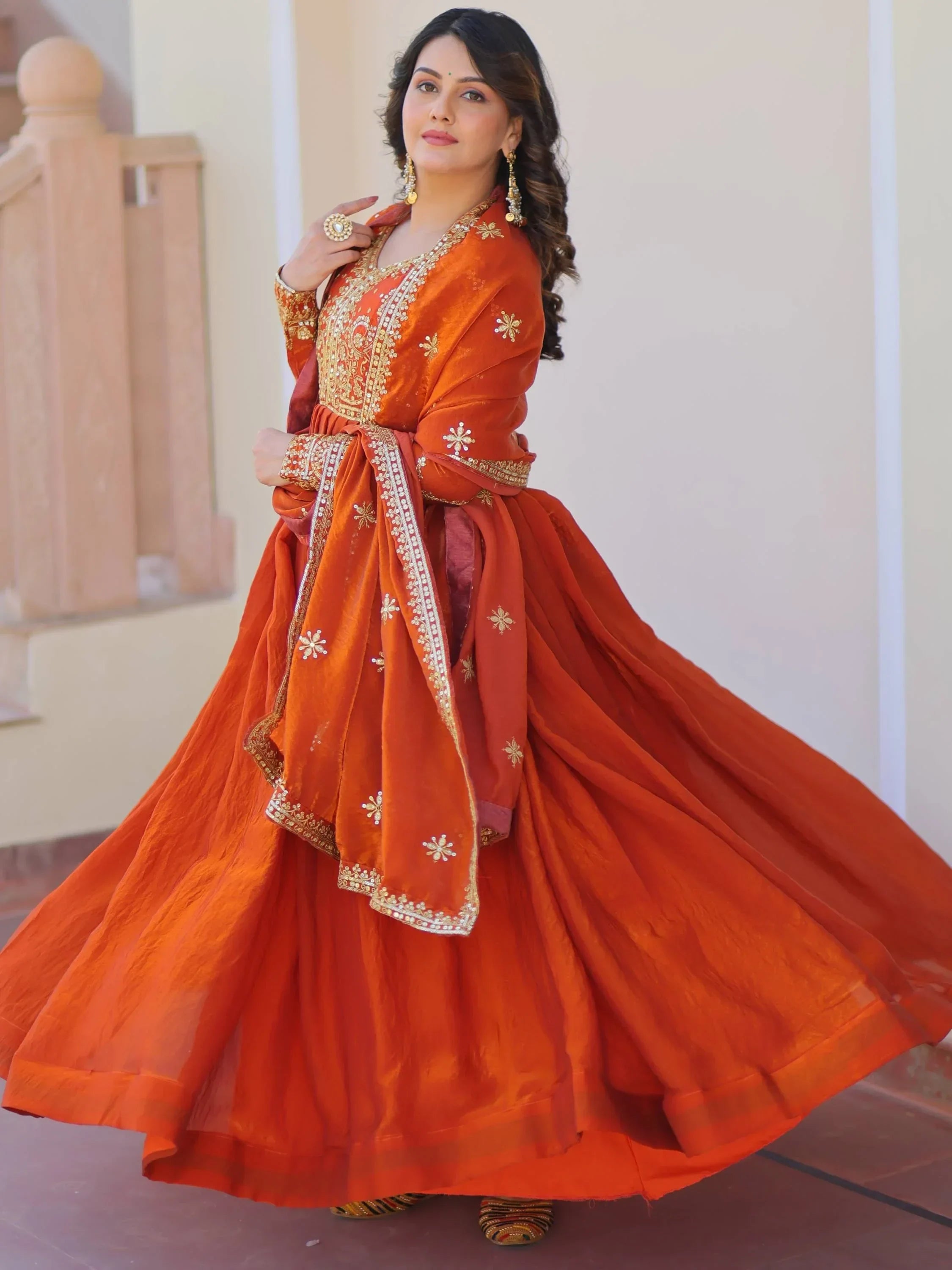 Woman in an orange embroidered lehenga choli with dupatta, traditional Indian ethnic wear