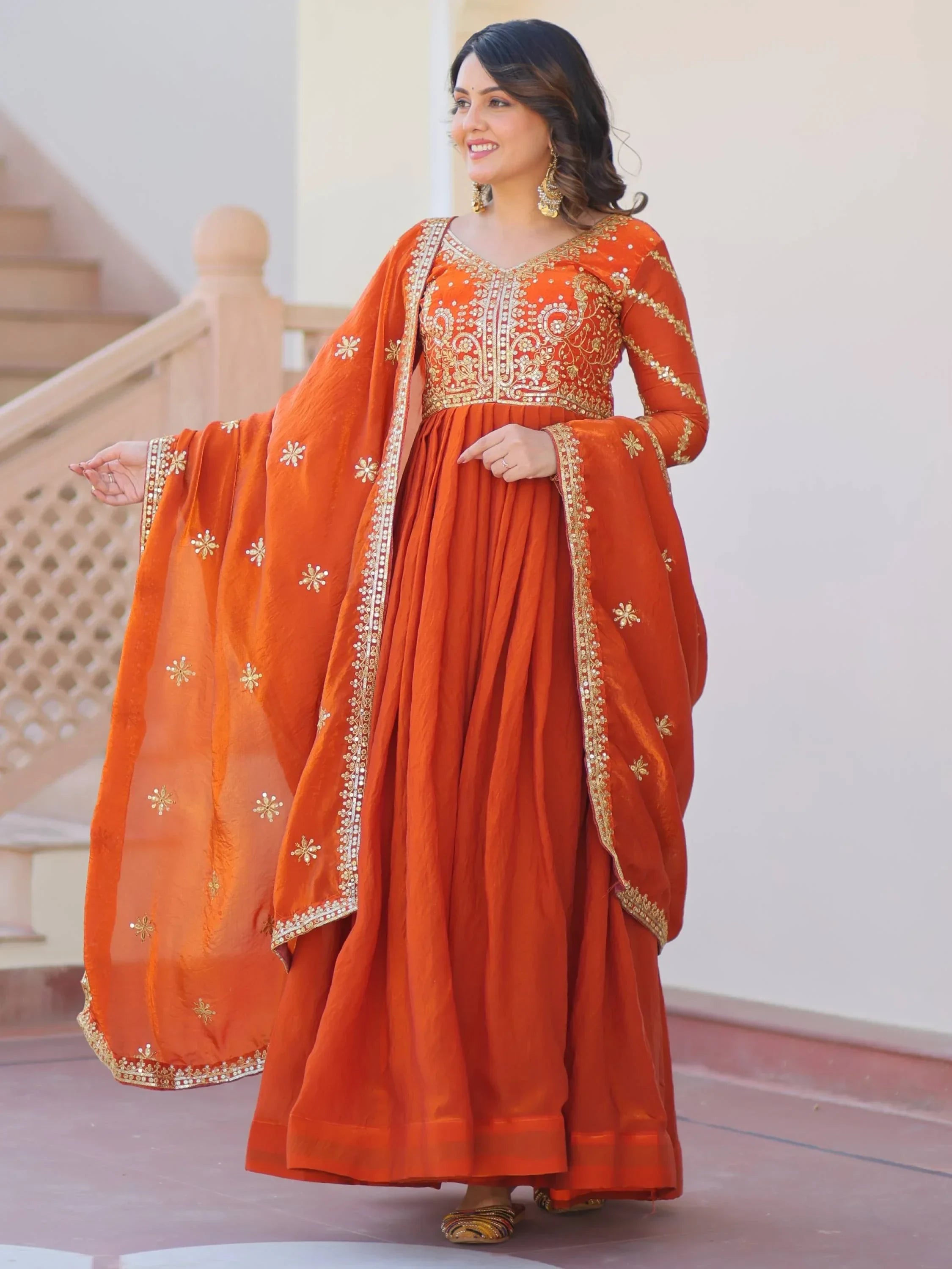Woman in orange embroidered anarkali ethnic gown with matching dupatta and gold jewelry