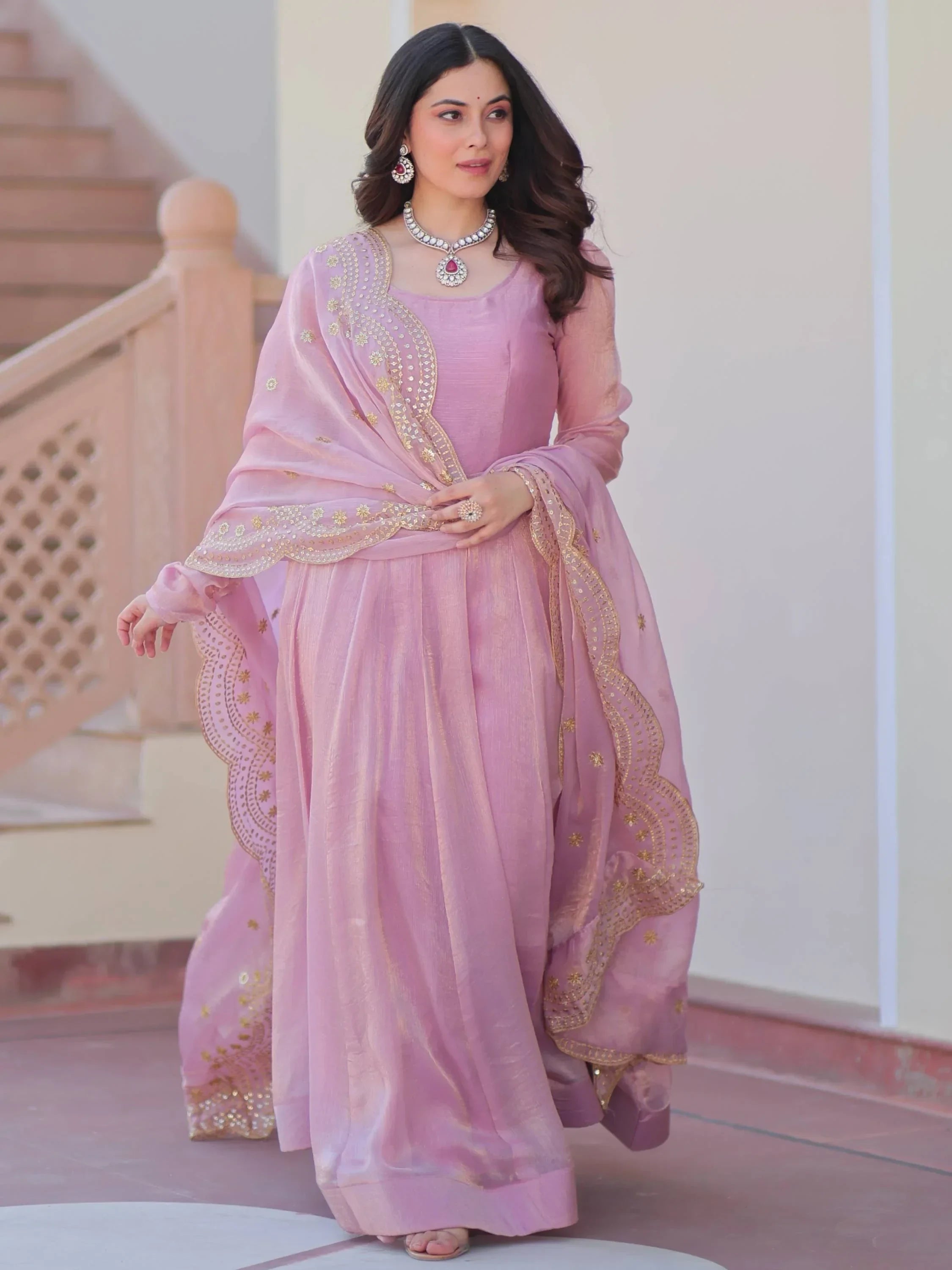 Woman in light pink Indian ethnic gown with gold embroidery and dupatta, traditional jewelry
