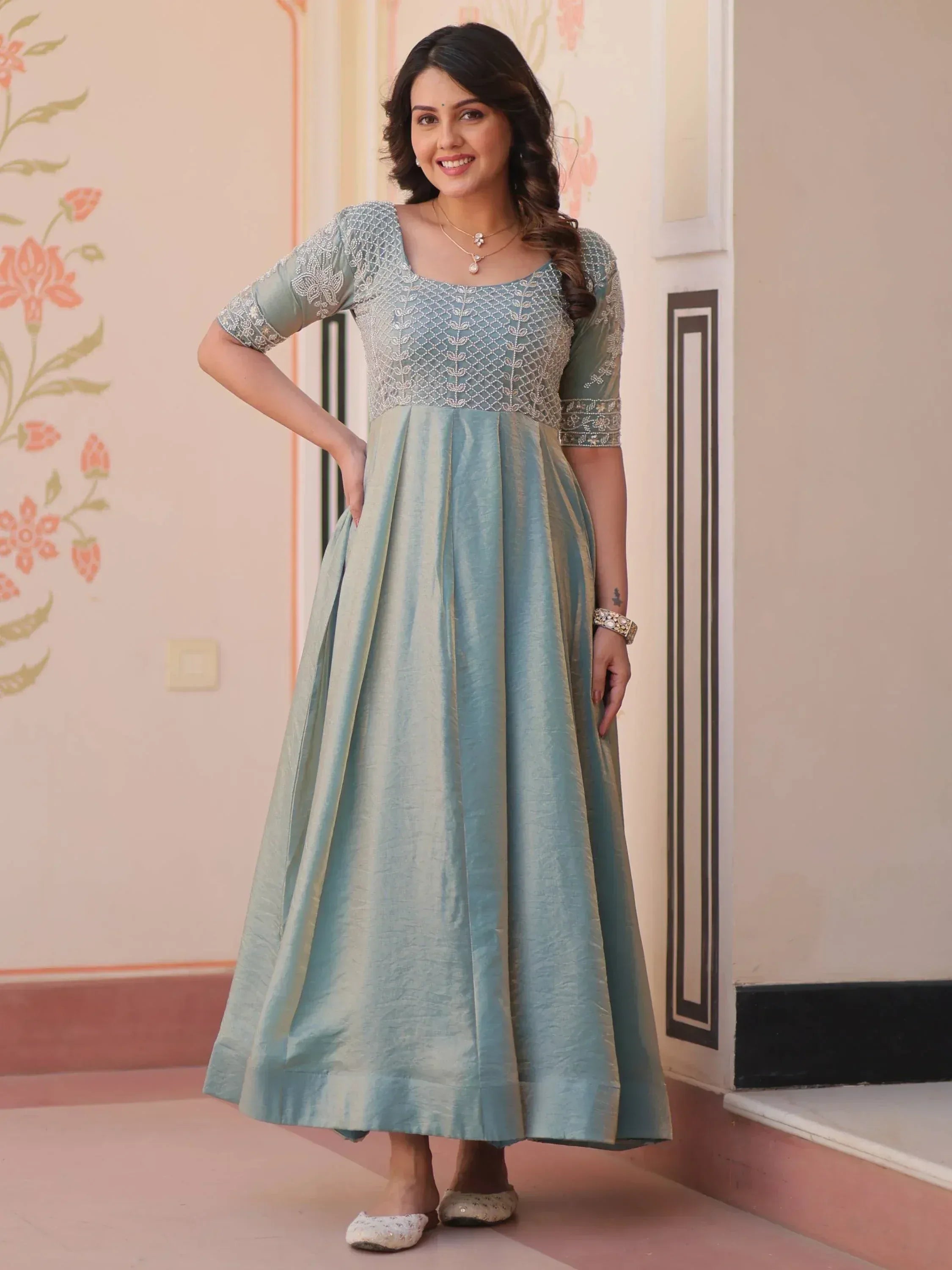 Woman in light blue embroidered ethnic gown with pleated skirt, perfect for Indian occasions
