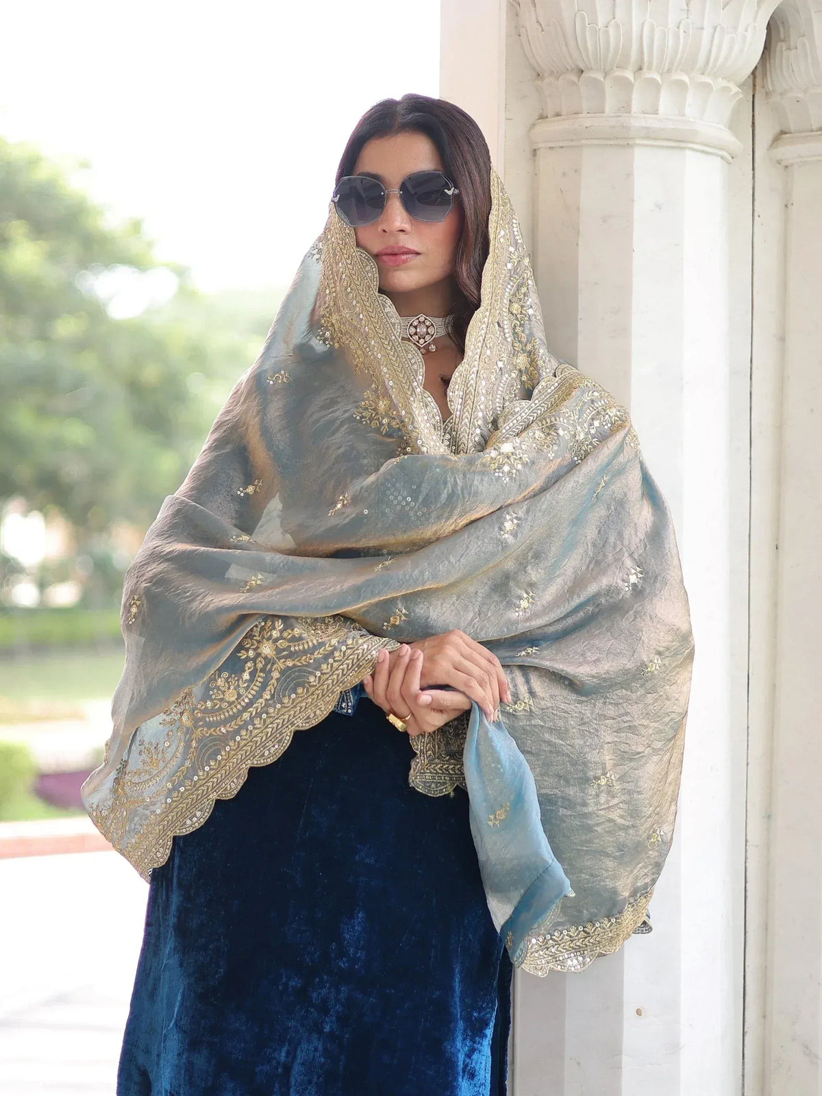 Elegant woman in blue velvet salwar kameez with gold-embroidered dupatta, styled for Indian ethnic wear.