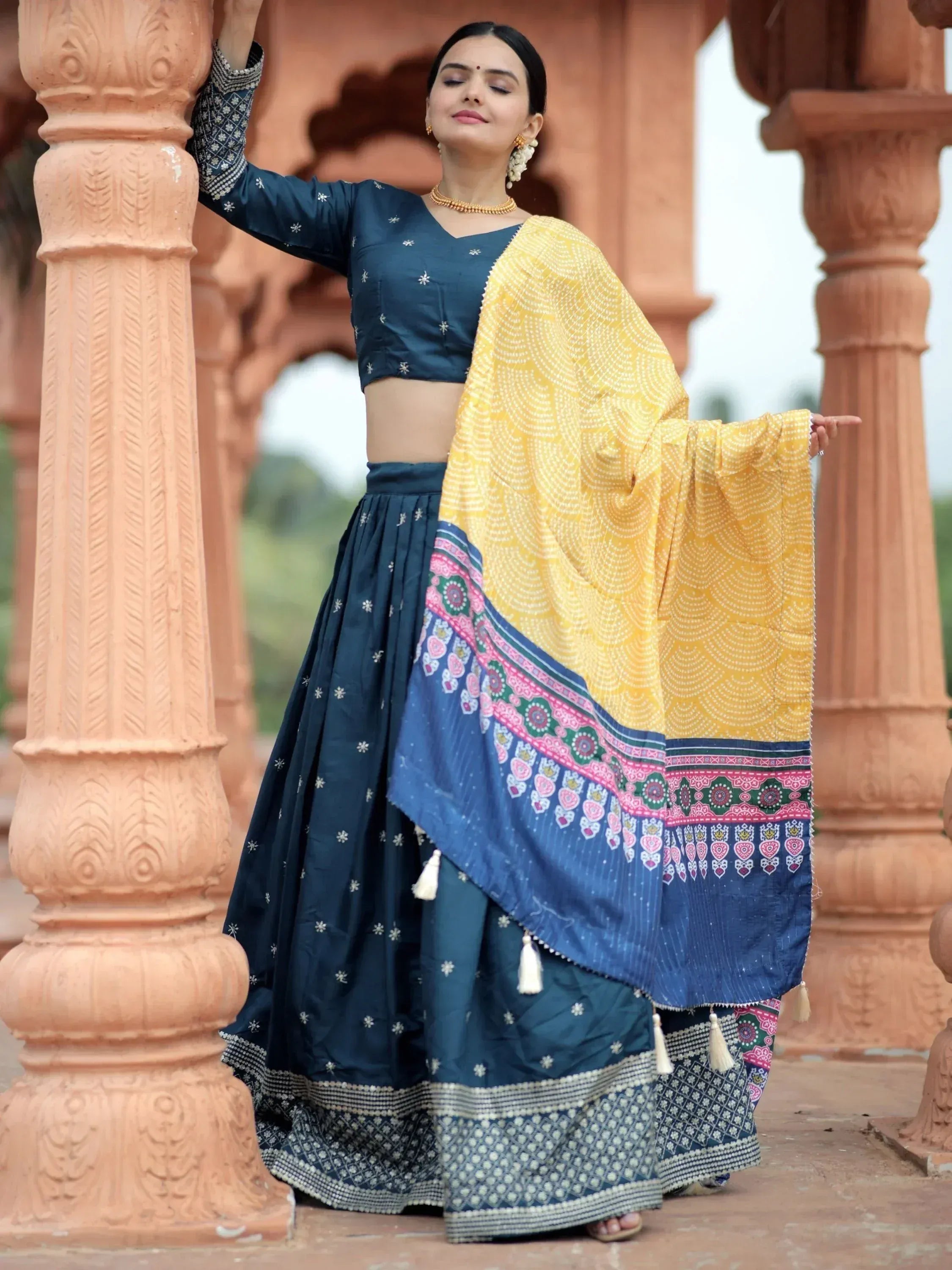 Woman in navy blue embroidered lehenga choli with yellow printed dupatta, traditional Indian ethnic wear