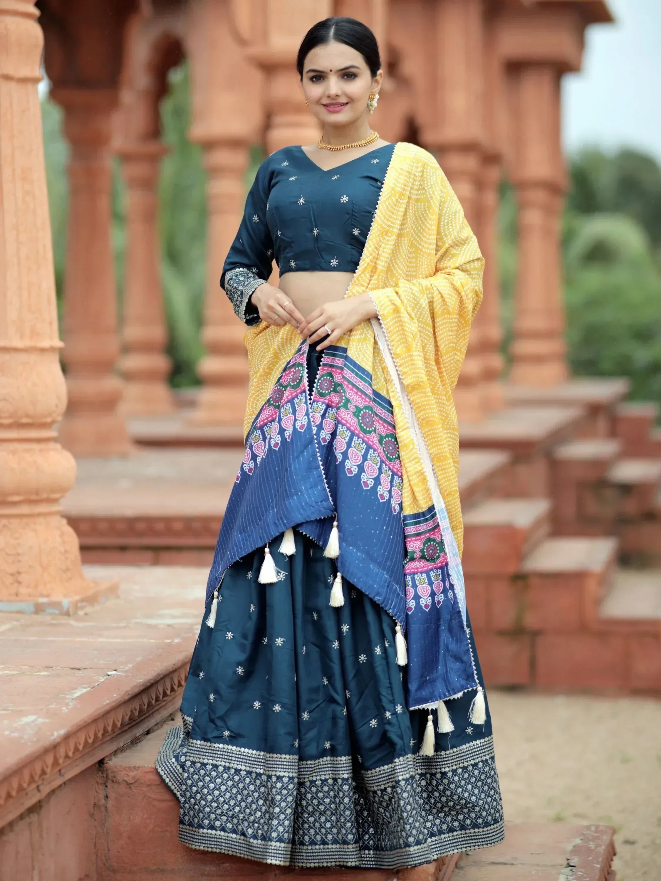 Woman in navy blue embroidered lehenga choli with yellow dupatta, traditional Indian ethnic wear