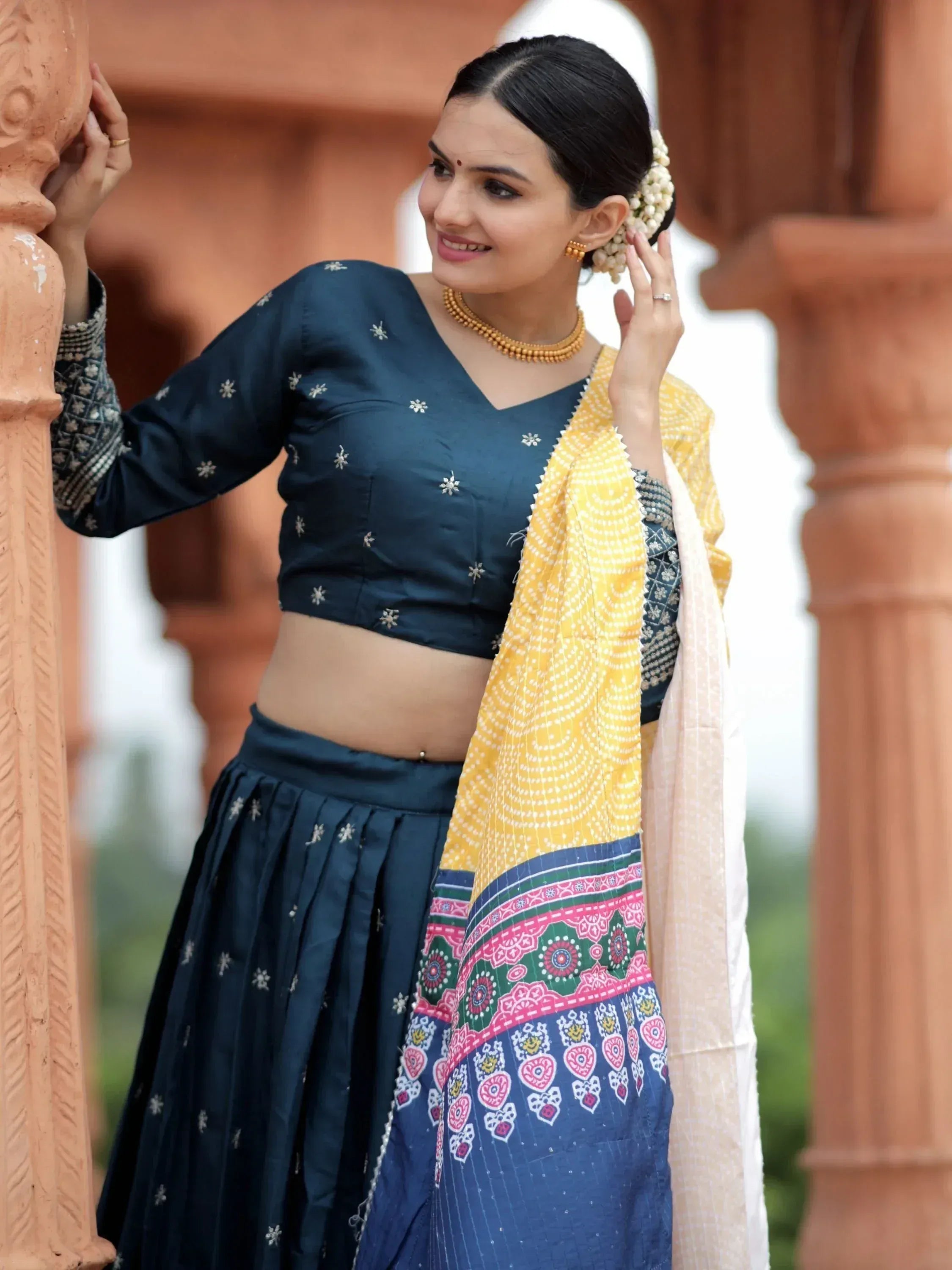 Woman in navy blue embroidered lehenga choli with yellow dupatta, traditional Indian ethnic wear