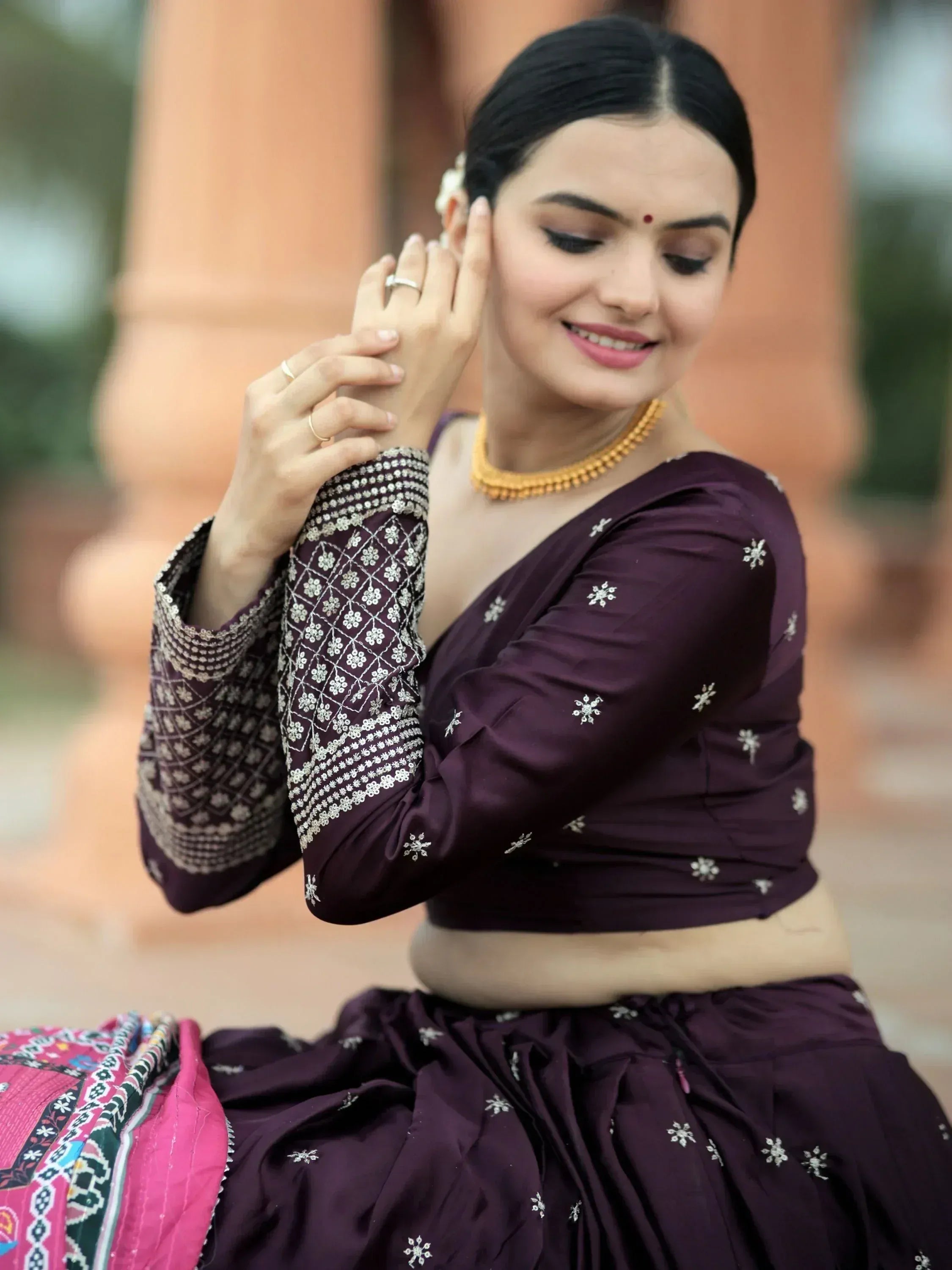 Woman in purple embroidered lehenga choli with gold jewelry, traditional Indian ethnic wear
