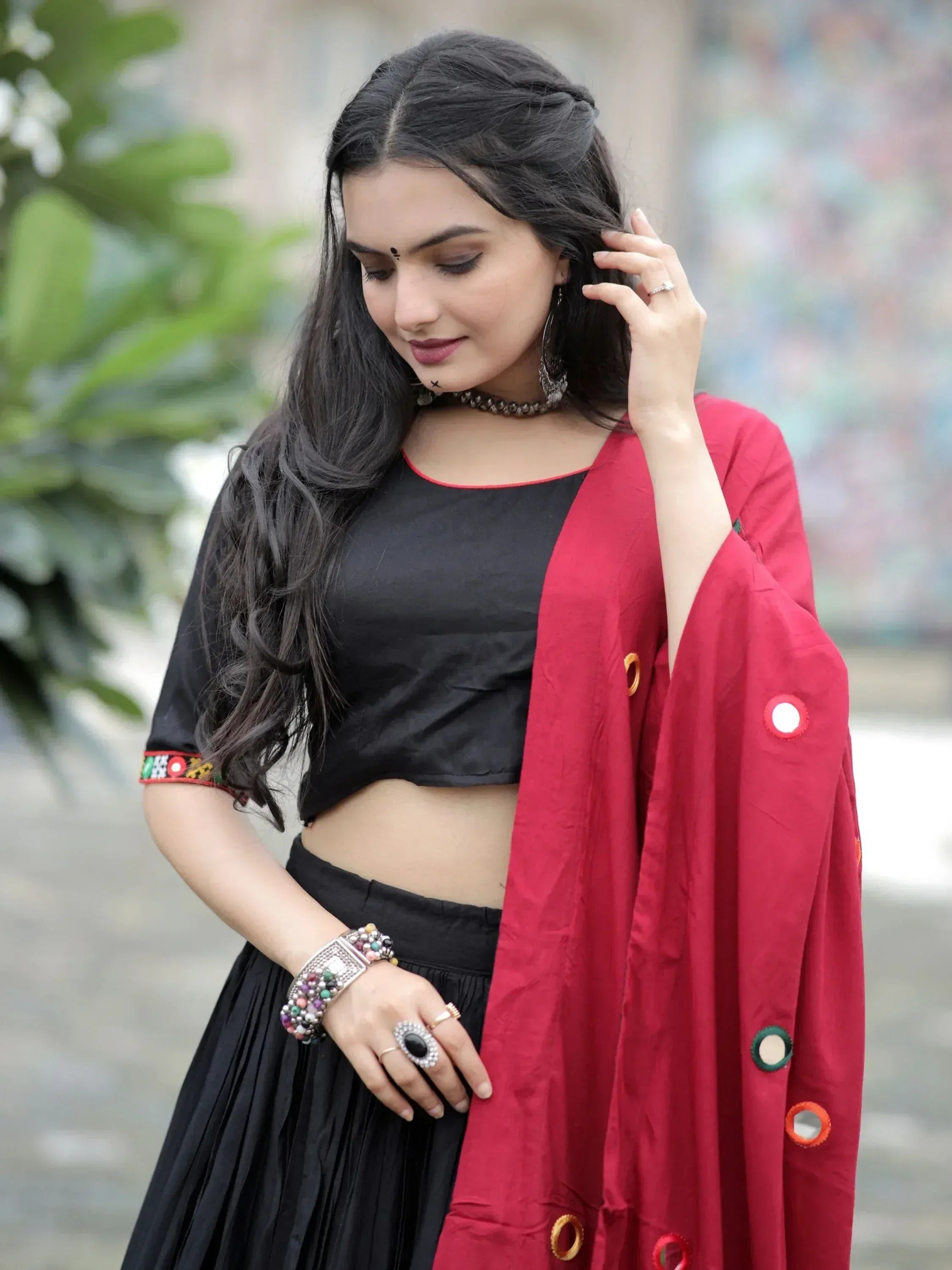 Woman in black crop top and pleated skirt with red mirror-work dupatta, ethnic Indian wear