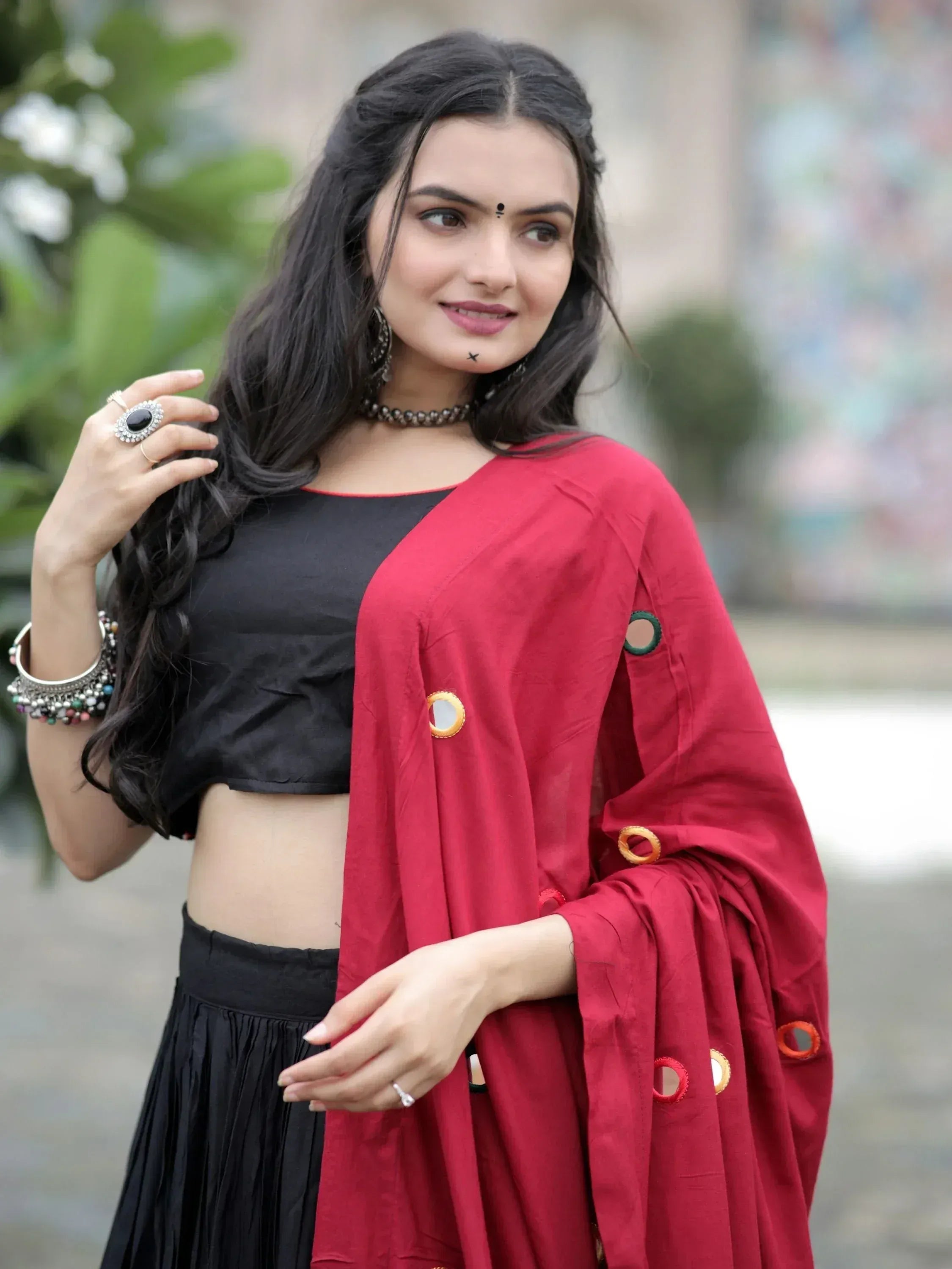 Woman in black crop top and skirt with red mirror-work dupatta, ethnic Indian wear
