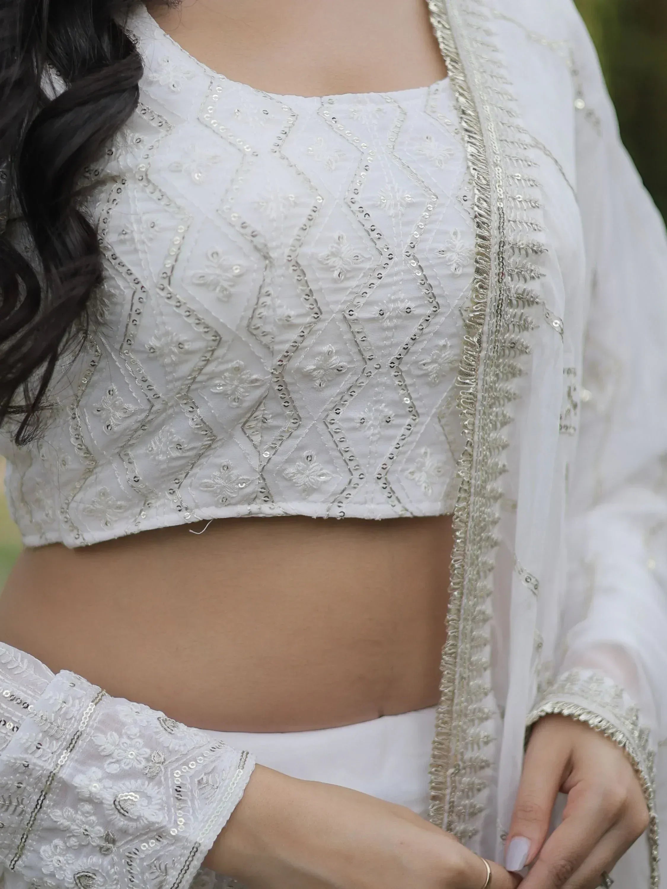 White embroidered crop top with silver sequins and floral detailing, paired with matching ethnic wear.