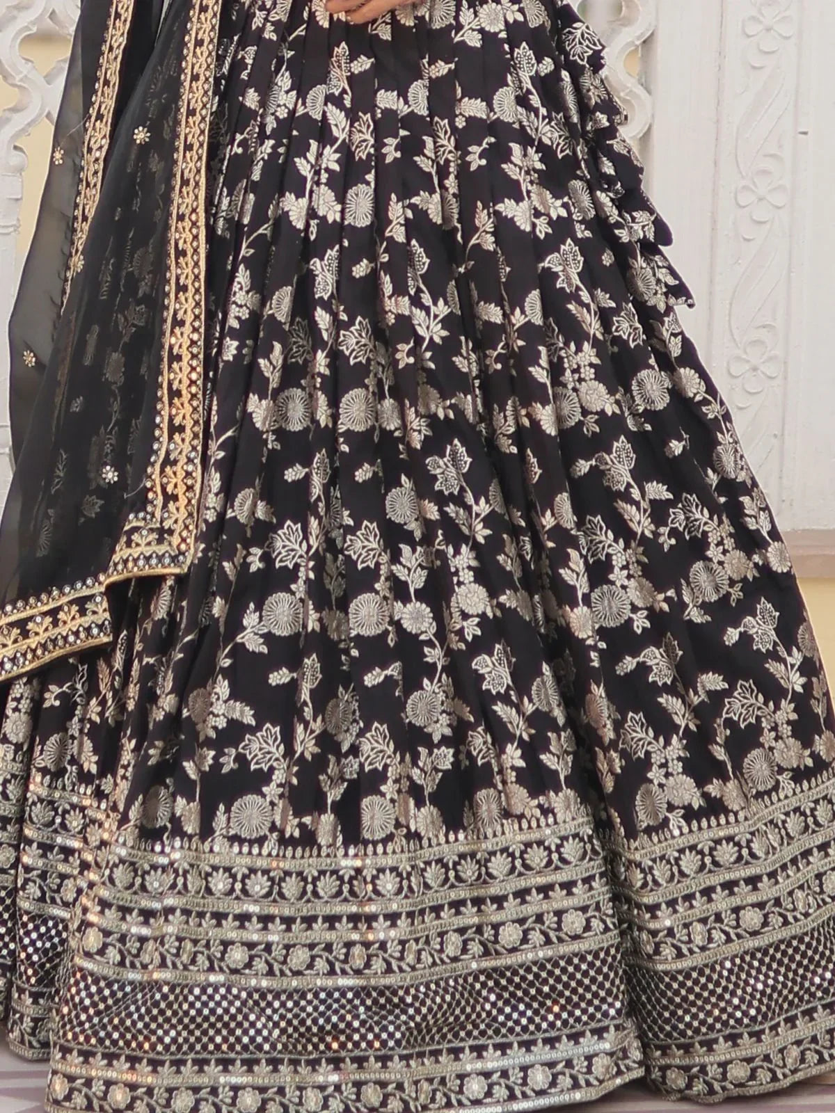 Black floral embroidered lehenga choli with gold detailing and ruffled hem, perfect for Indian ethnic wear.