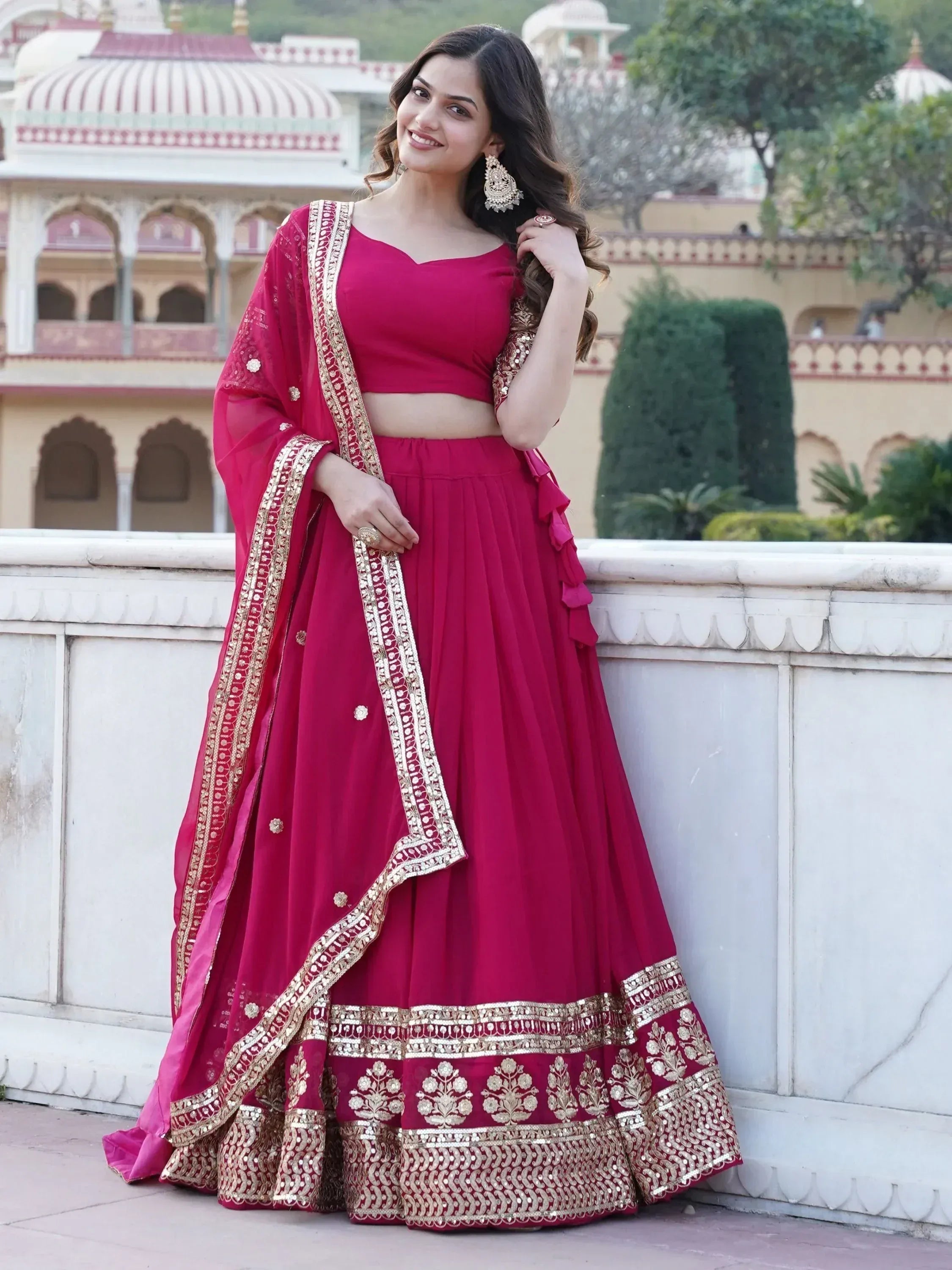 Woman in maroon lehenga choli with gold embroidery, perfect for Indian weddings and festive occasions.