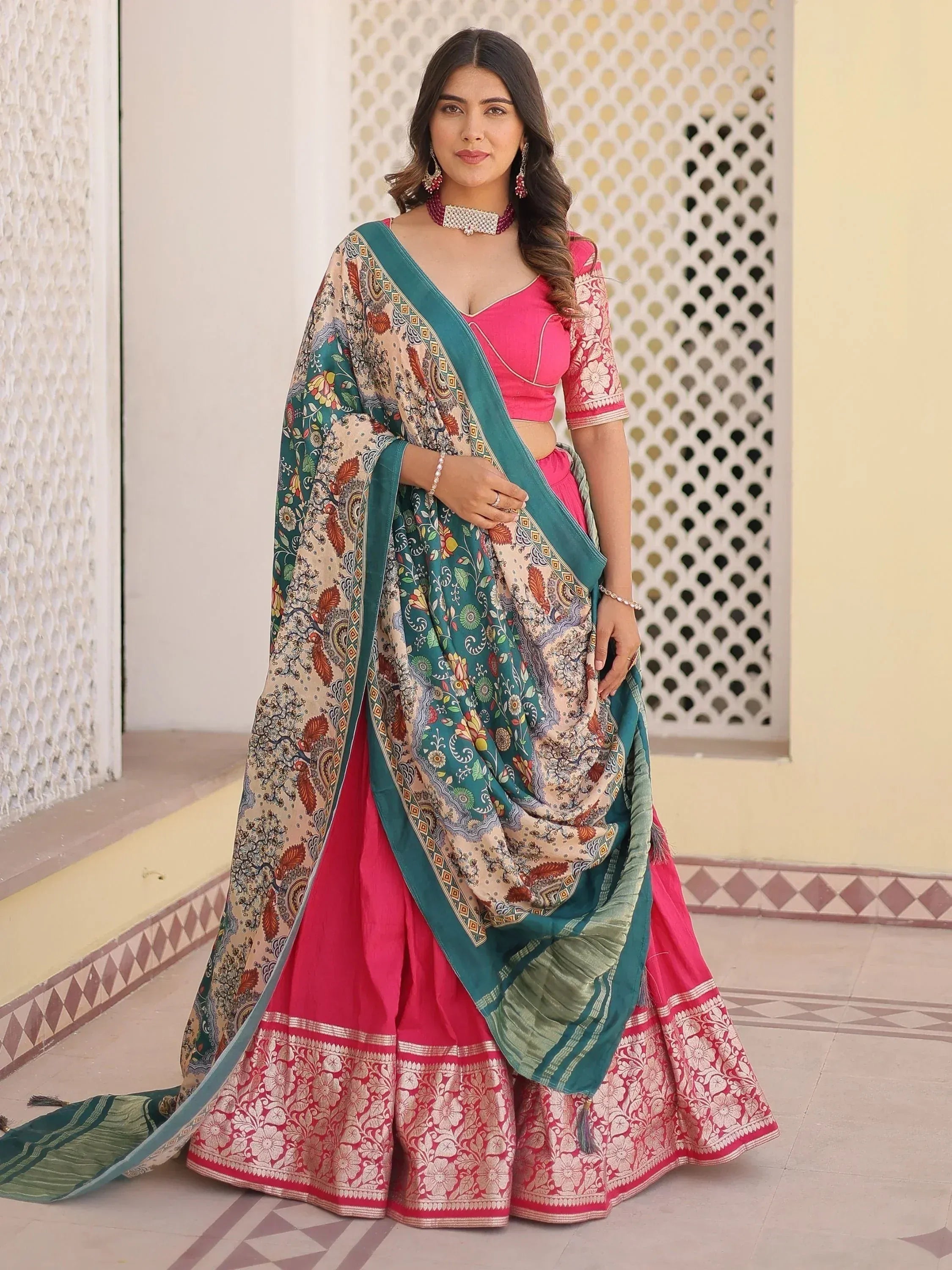 Woman in vibrant pink lehenga choli with floral dupatta, perfect for Indian ethnic wear occasions.