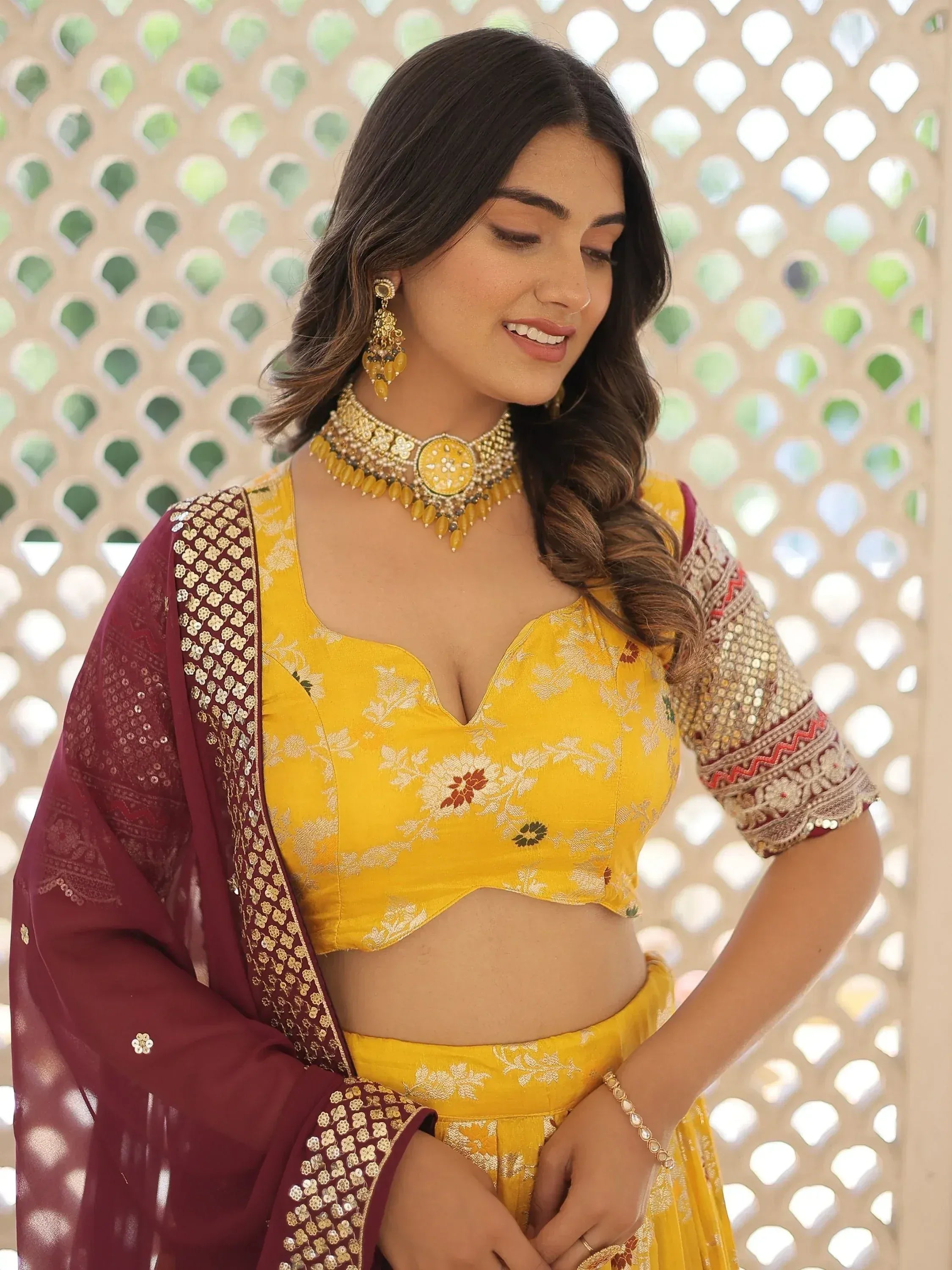 Yellow floral lehenga choli with maroon dupatta and gold jewelry