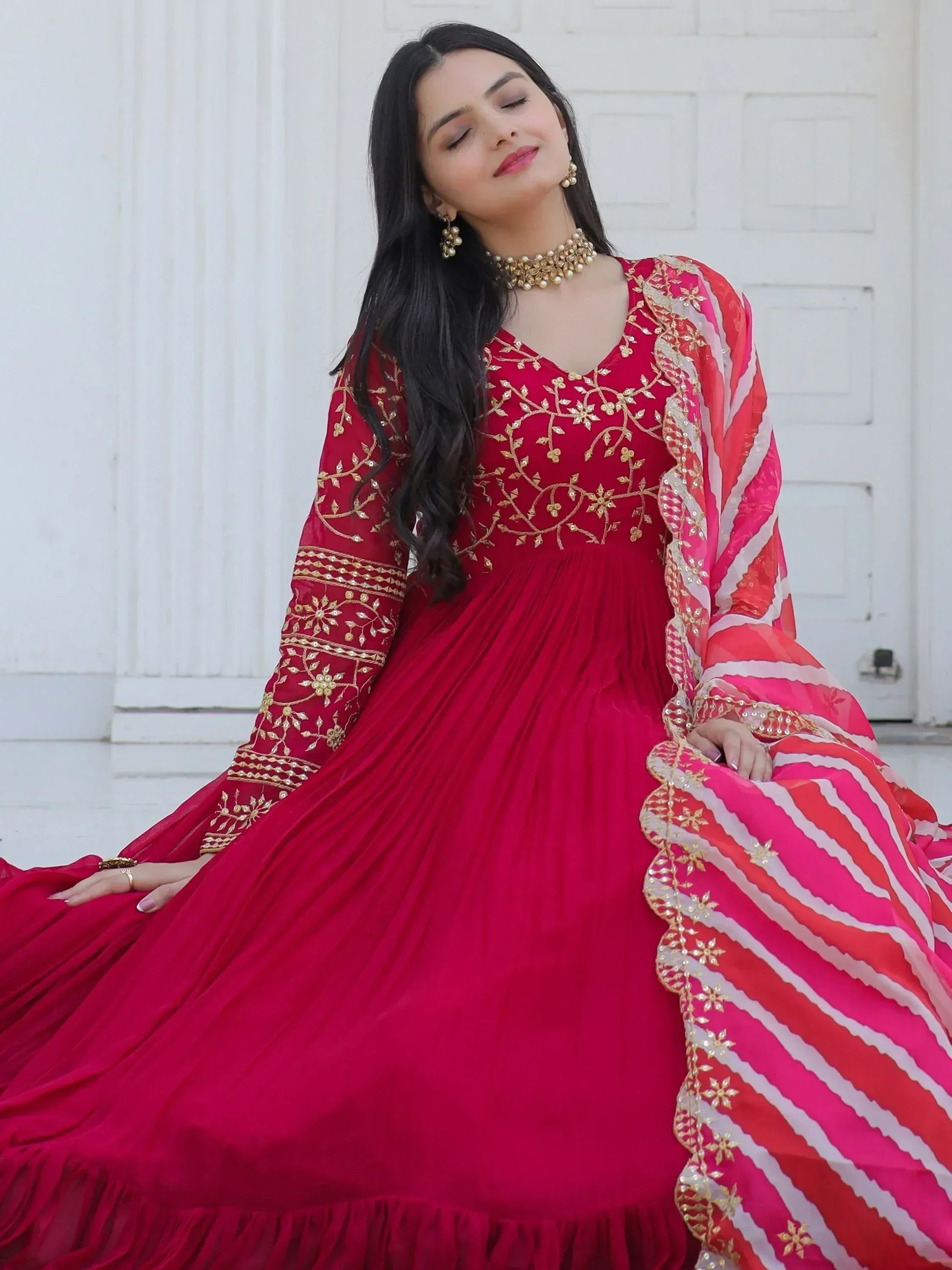 Red embroidered ethnic gown with gold detailing and striped dupatta, perfect for Indian celebrations