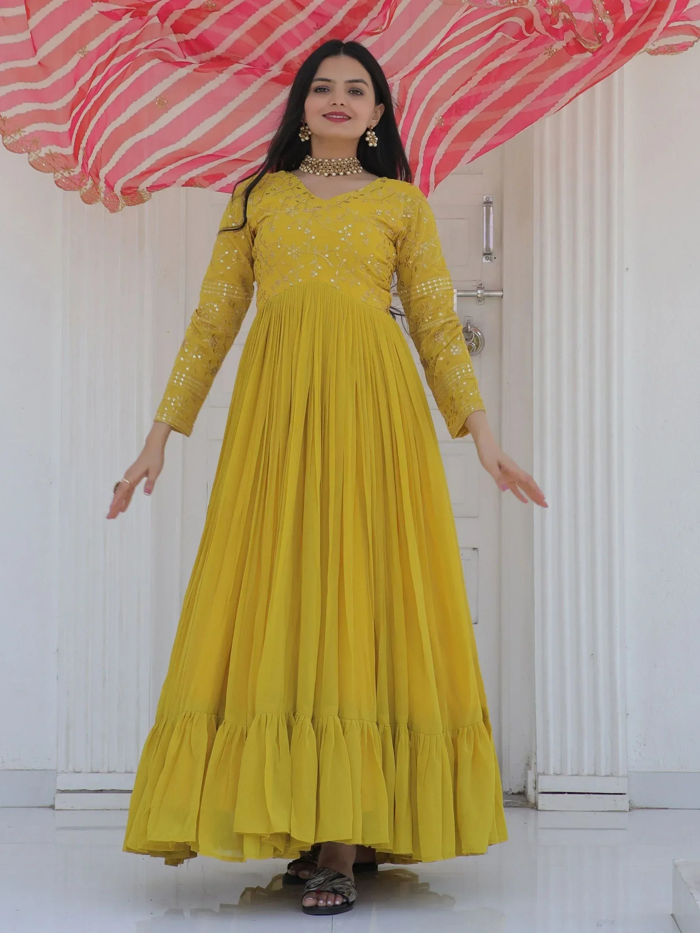 Yellow ethnic gown with sequin embroidery and pleated skirt, paired with pink striped dupatta