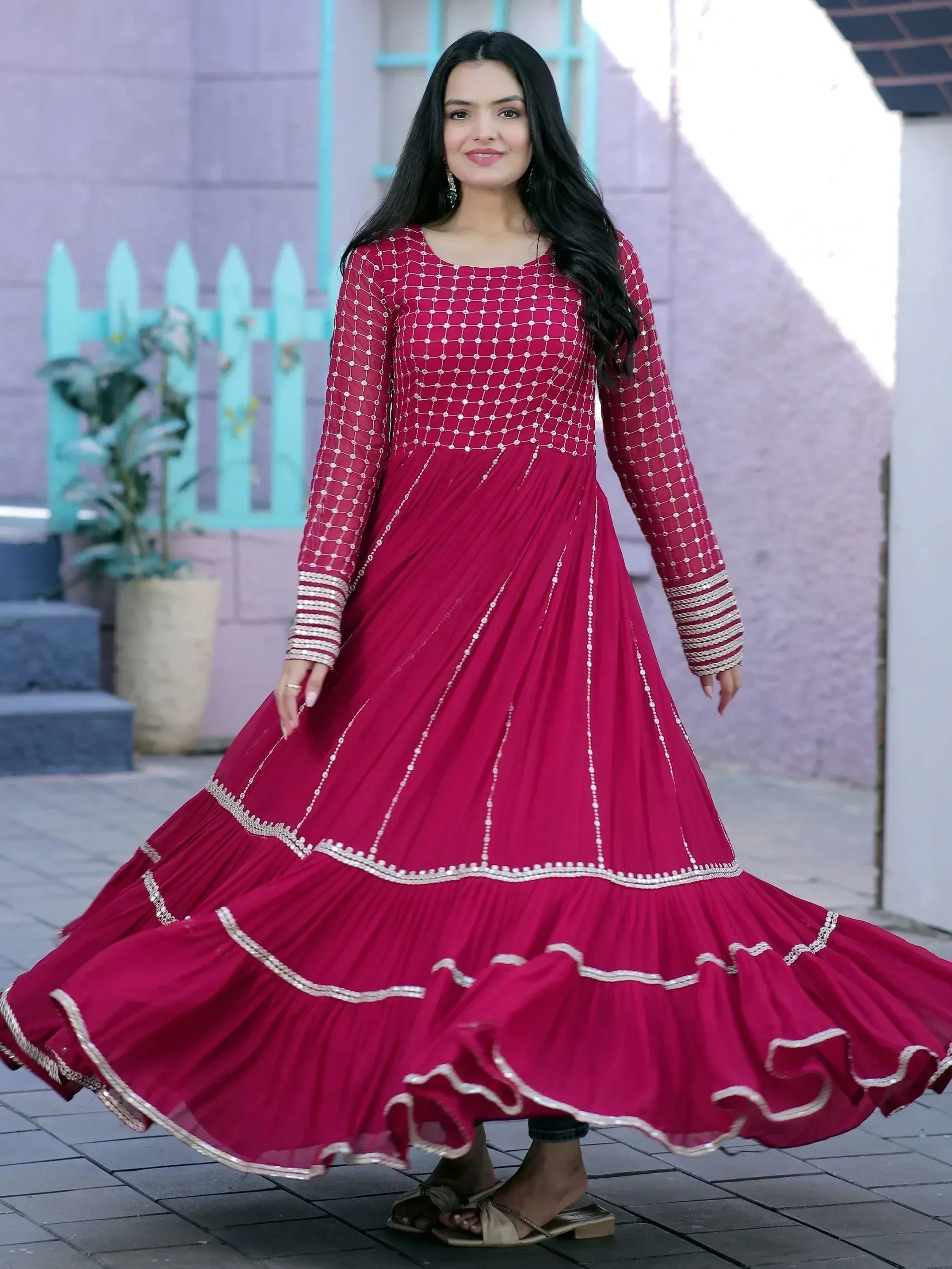 Woman in maroon ethnic gown with silver embroidery, pleated skirt, and long sleeves for festive occasions