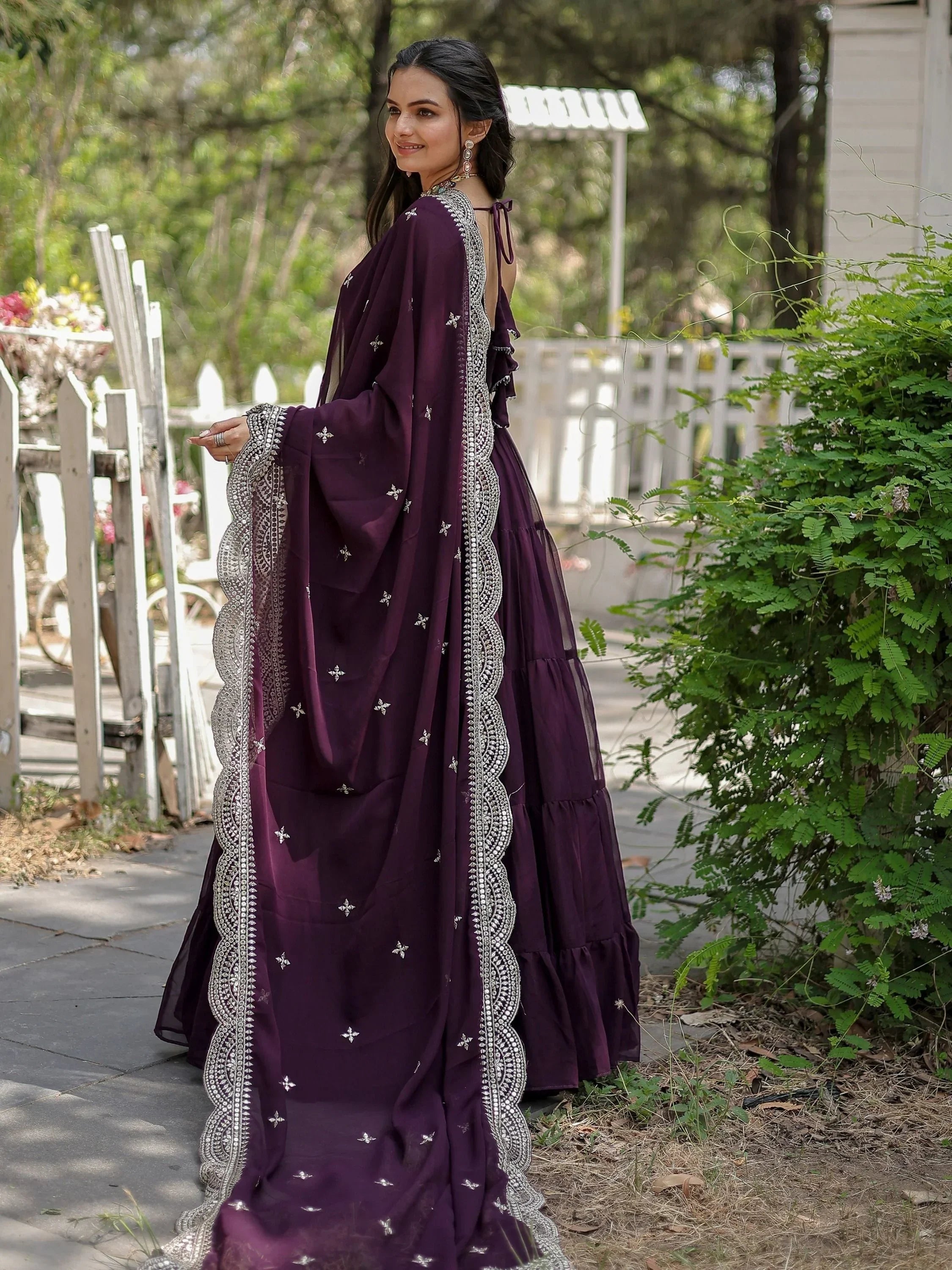 Woman in a purple embroidered lehenga choli with dupatta, standing outdoors