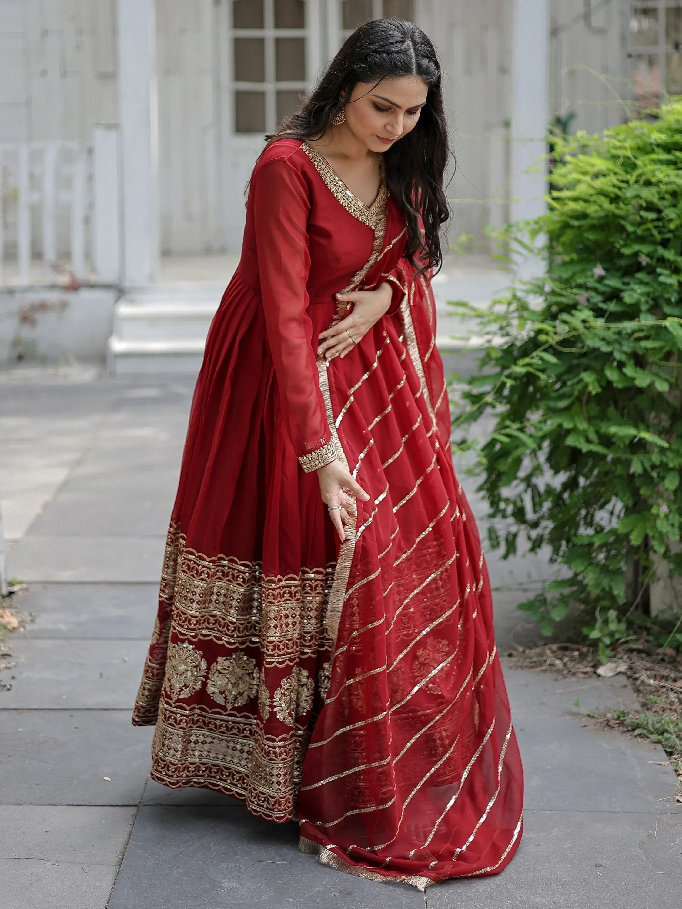 Woman in maroon embroidered Anarkali suit with gold detailing and matching dupatta