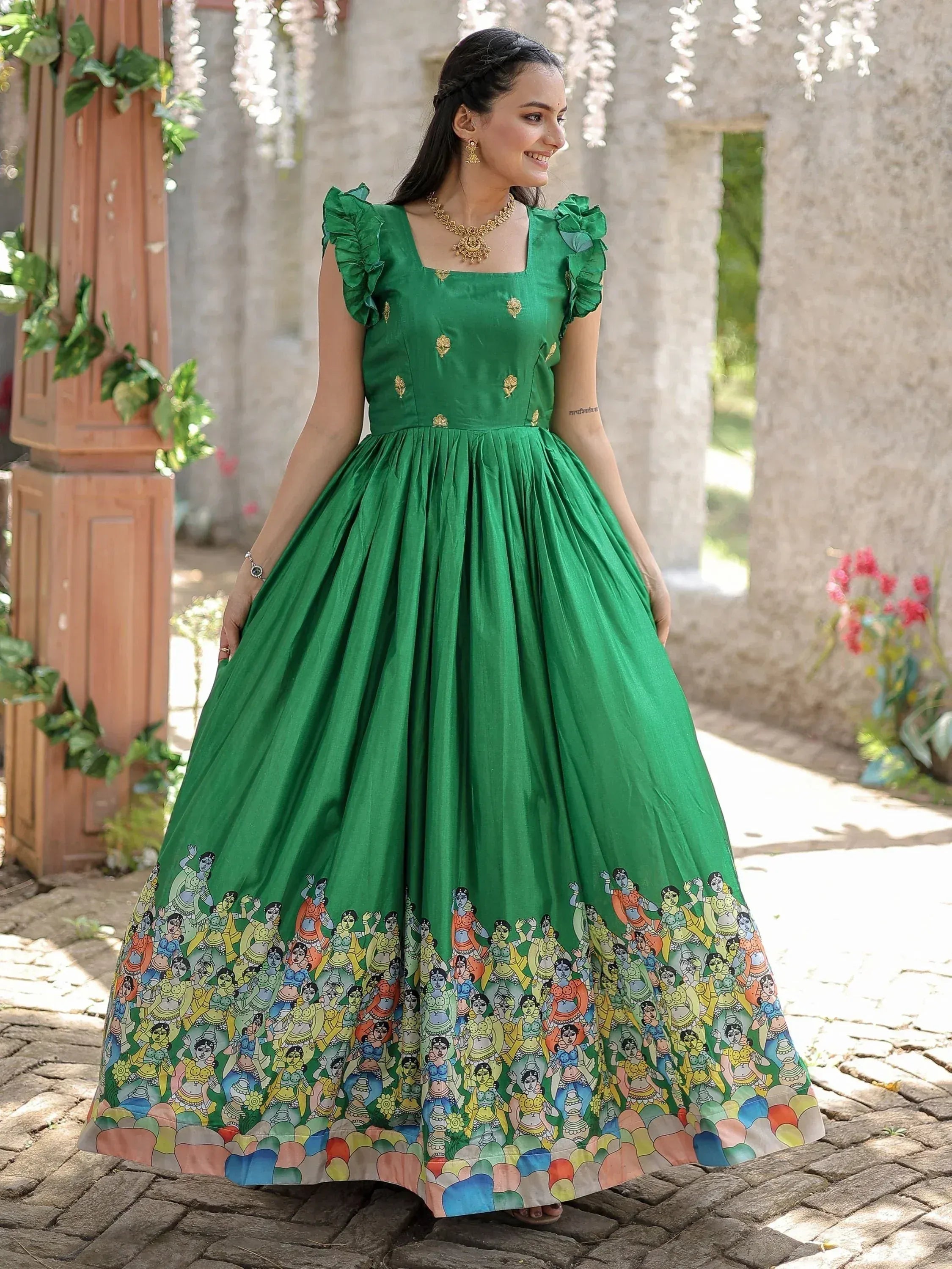 Emerald green ethnic gown with ruffle sleeves and colorful folk art print, perfect for Indian occasions.