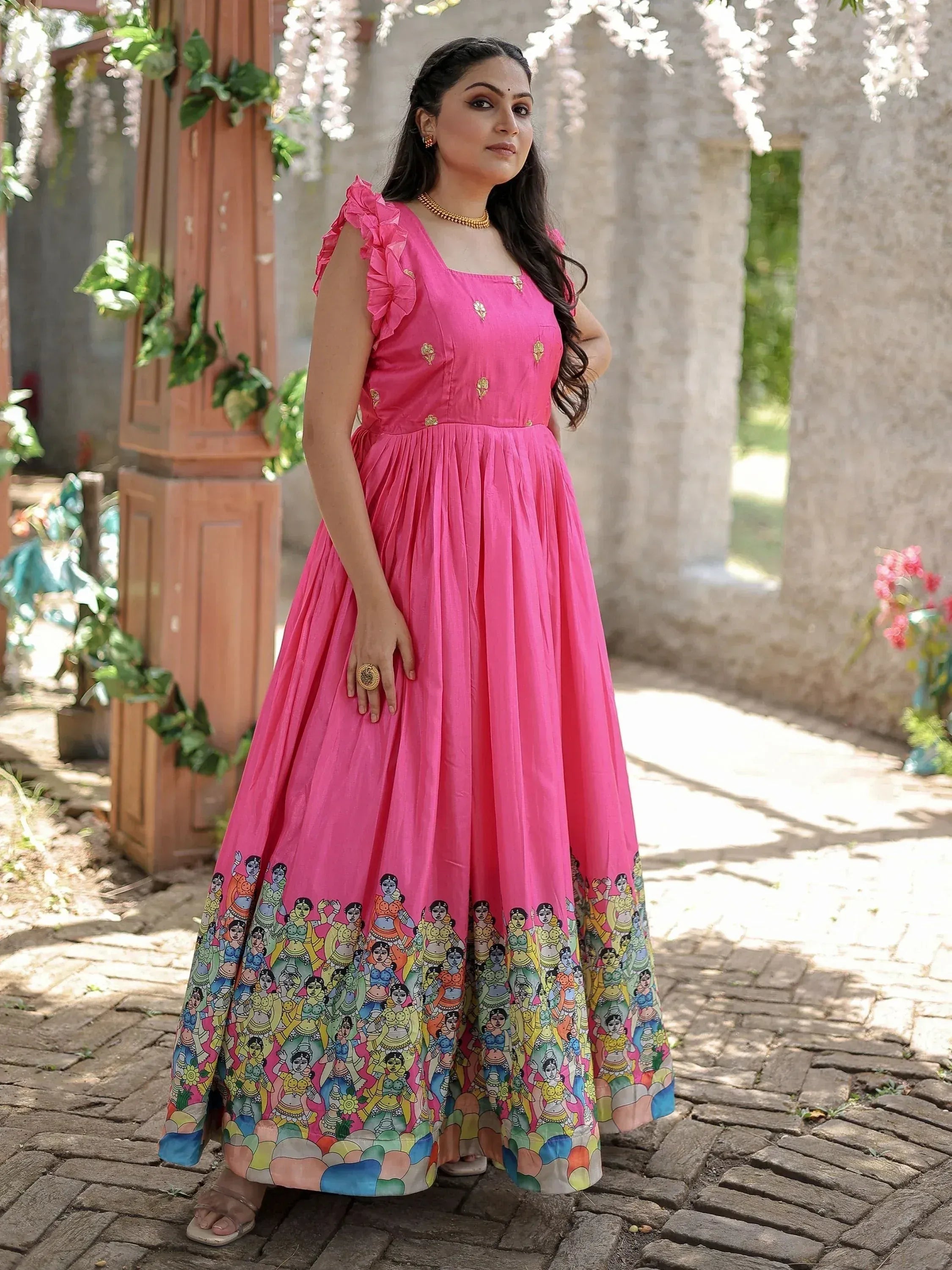 Pink ethnic gown with ruffle sleeves and colorful folk art print, perfect for Indian occasions
